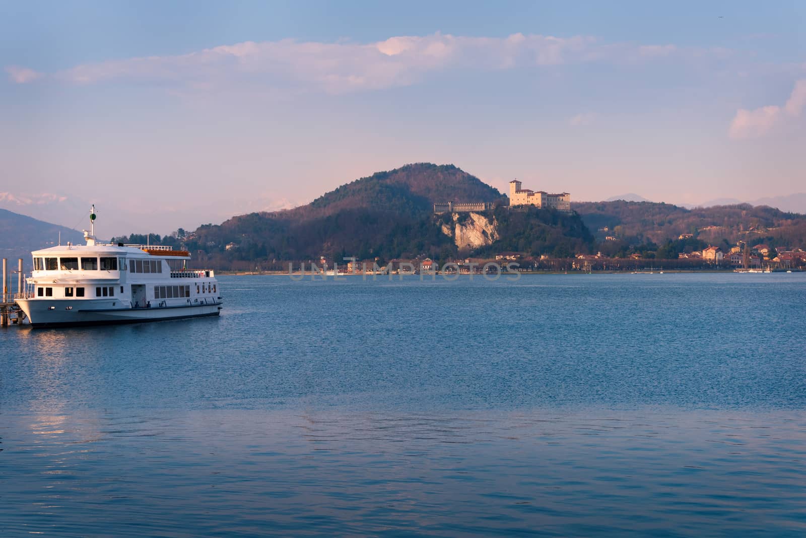 In the picture boat moored at the port of Arona, Maggiore Lake and in the background the fortress of Angera.