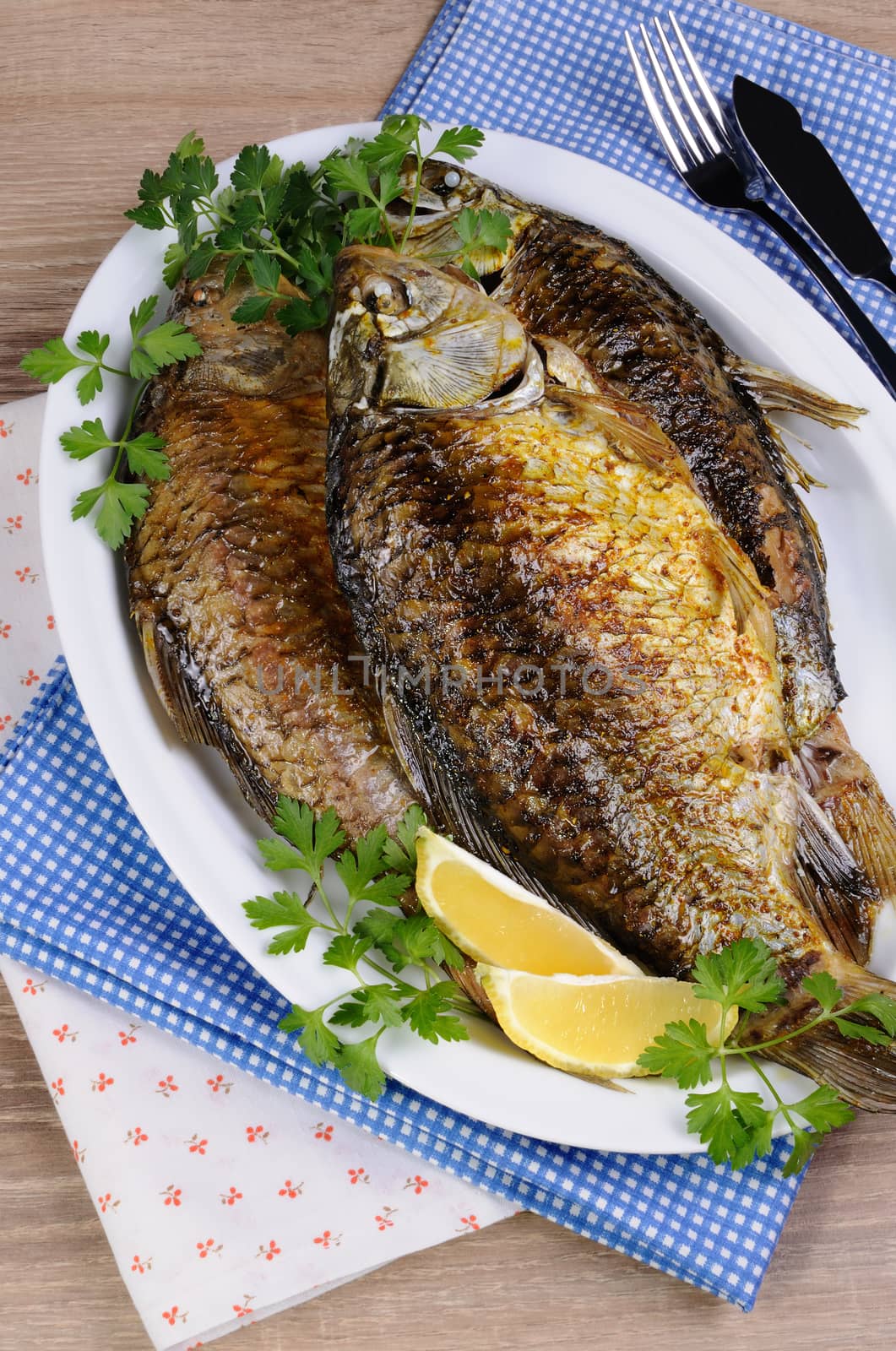 Fried crucian carp in a plate on the table with napkins