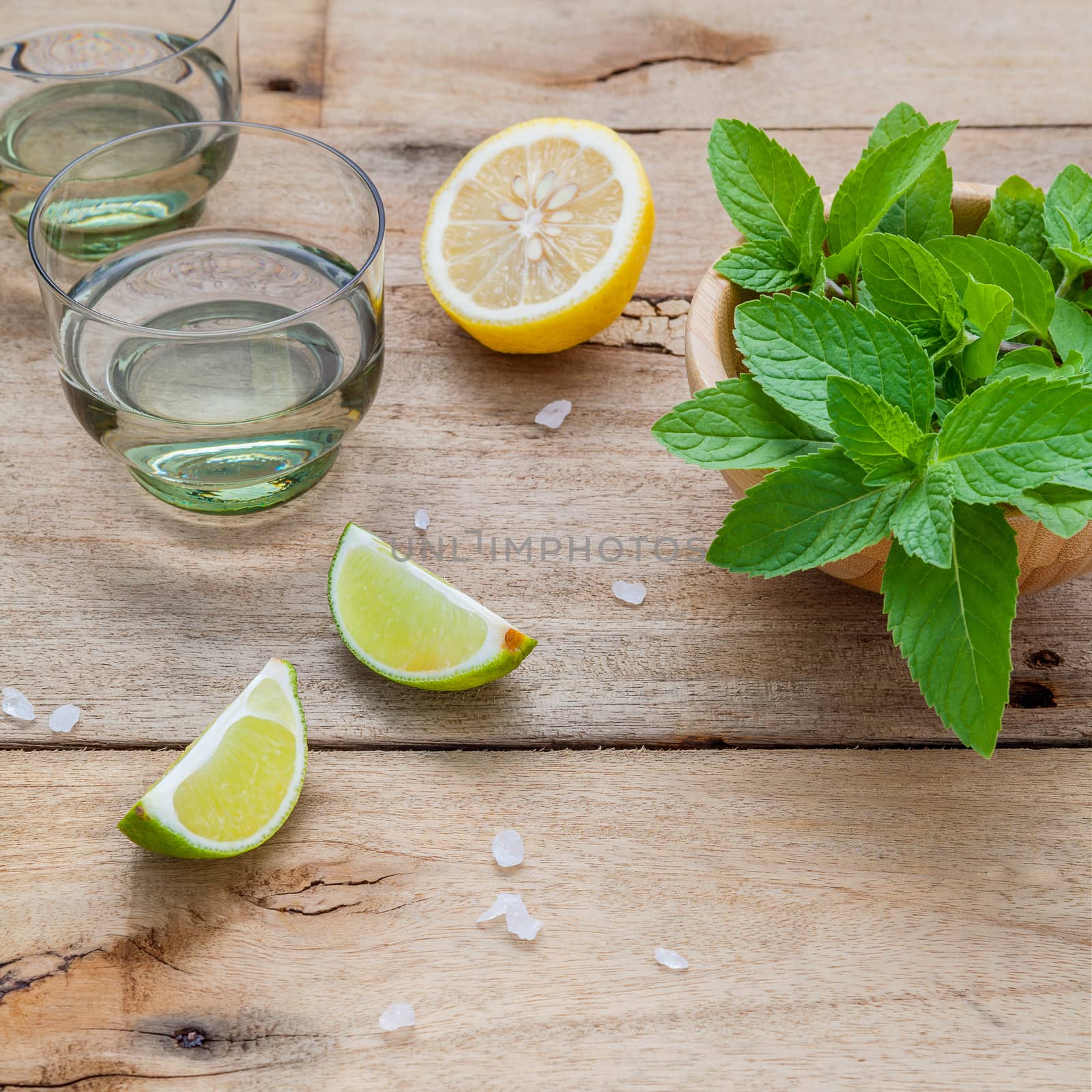 Ingredients for making mojitos mint leaves, lime,lemon and vodka on rustic background.