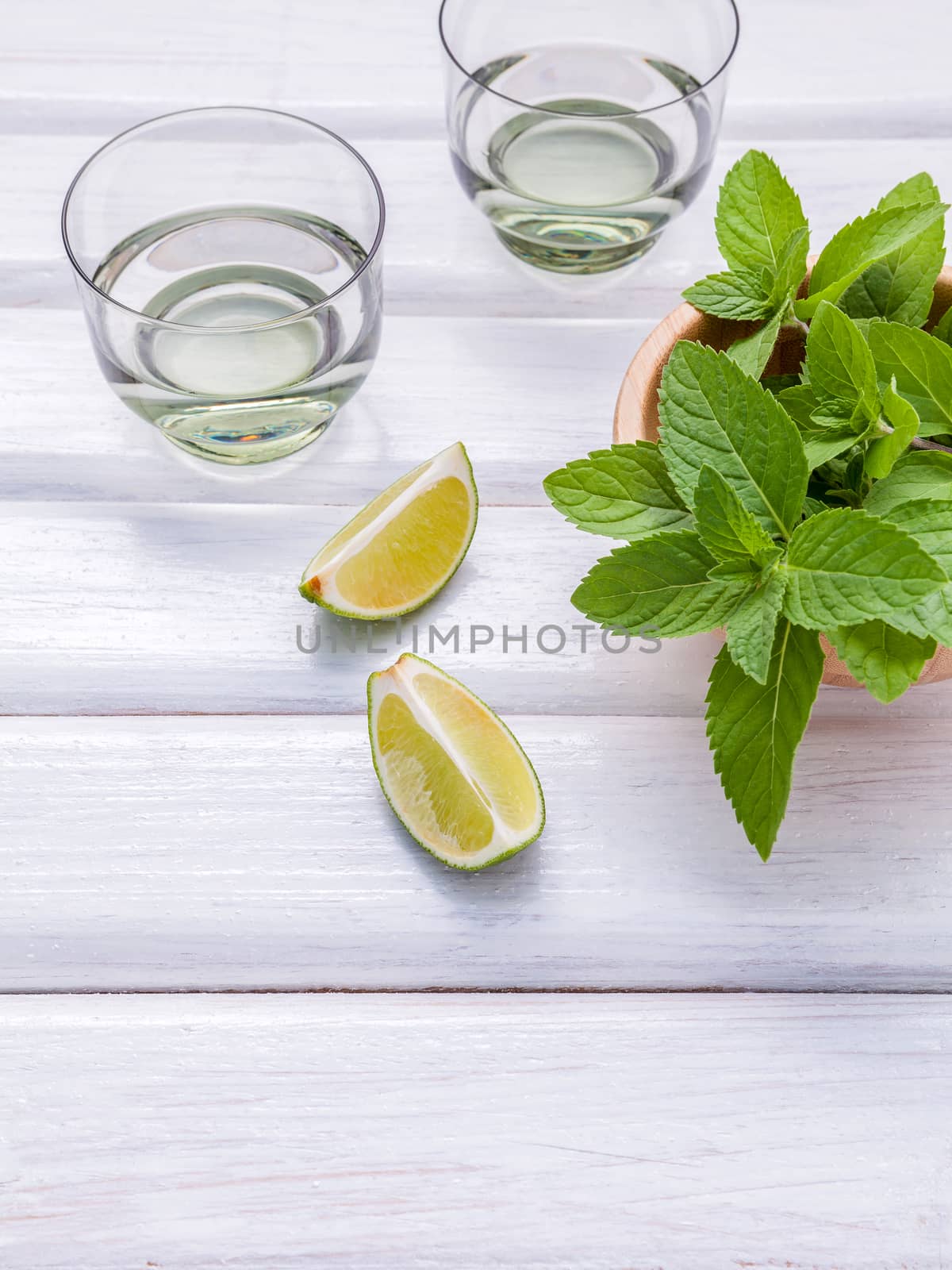 Ingredients for making mojitos mint leaves, lime,lemon and vodka on rustic background.
