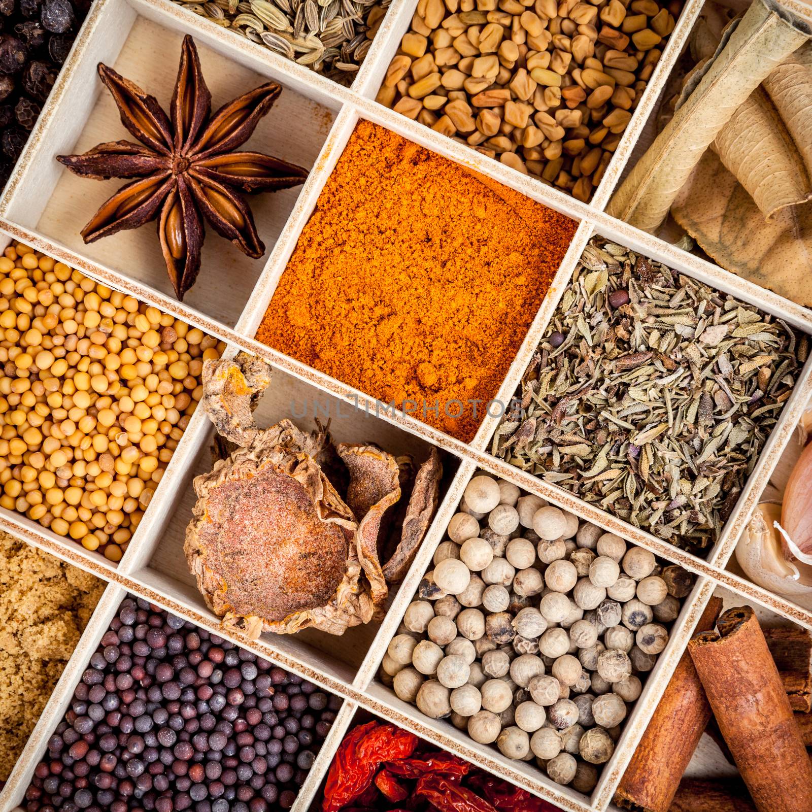 Assortment of spices food cooking ingredients in wooden box set up on wooden table.