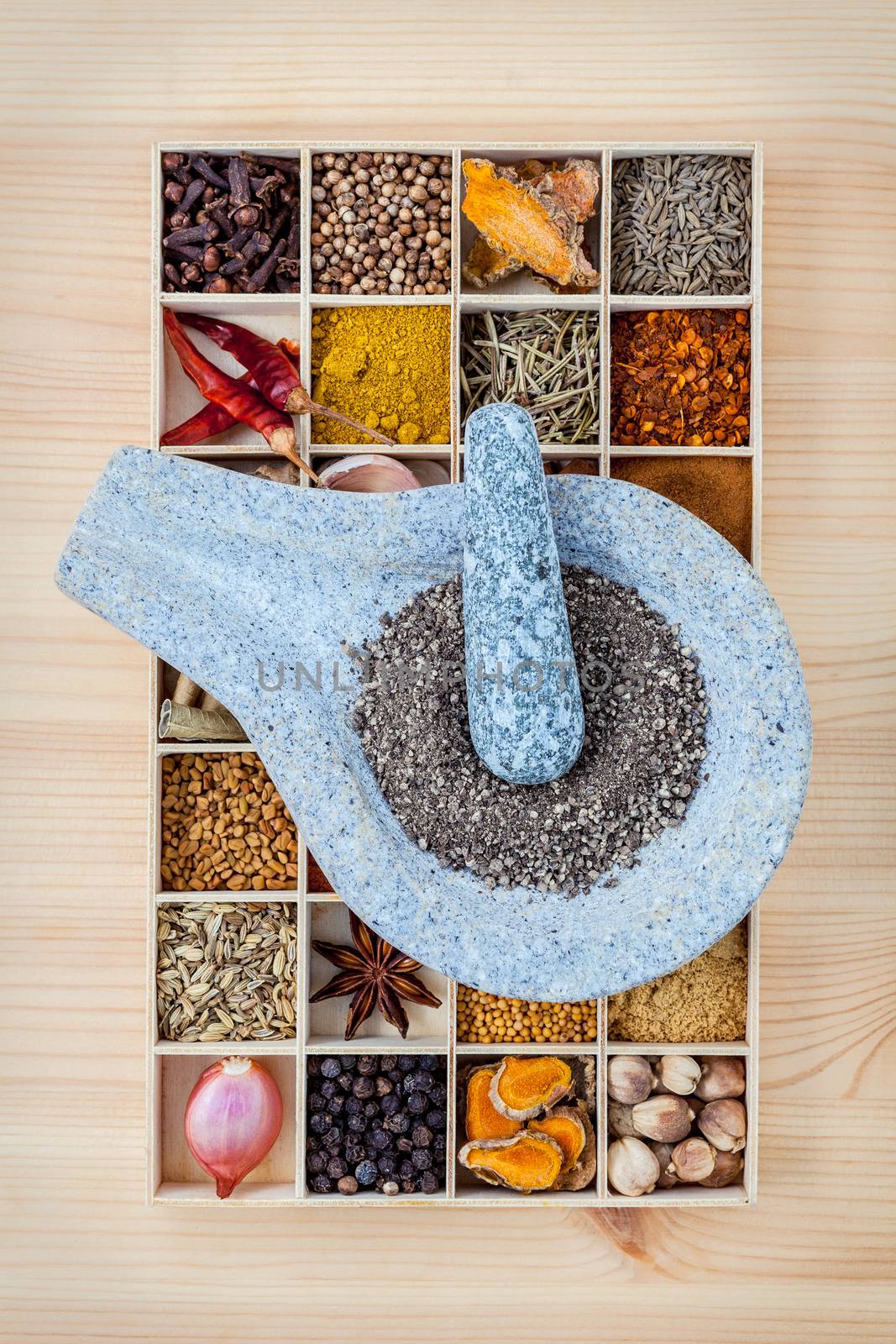 Assortment of spices food cooking ingredients in wooden box and mortar  set up on wooden table.