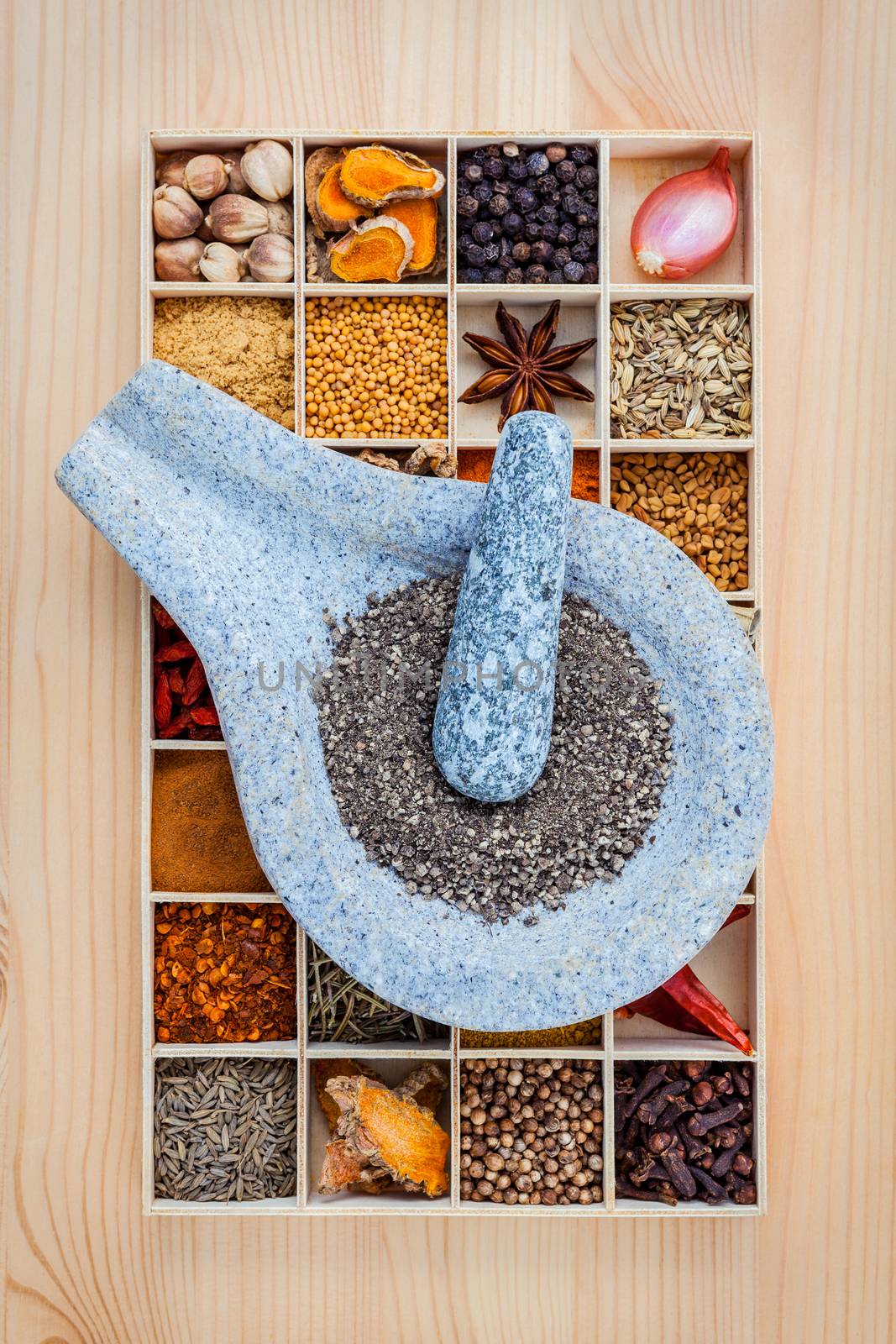 Assortment of spices food cooking ingredients in wooden box and mortar  set up on wooden table.