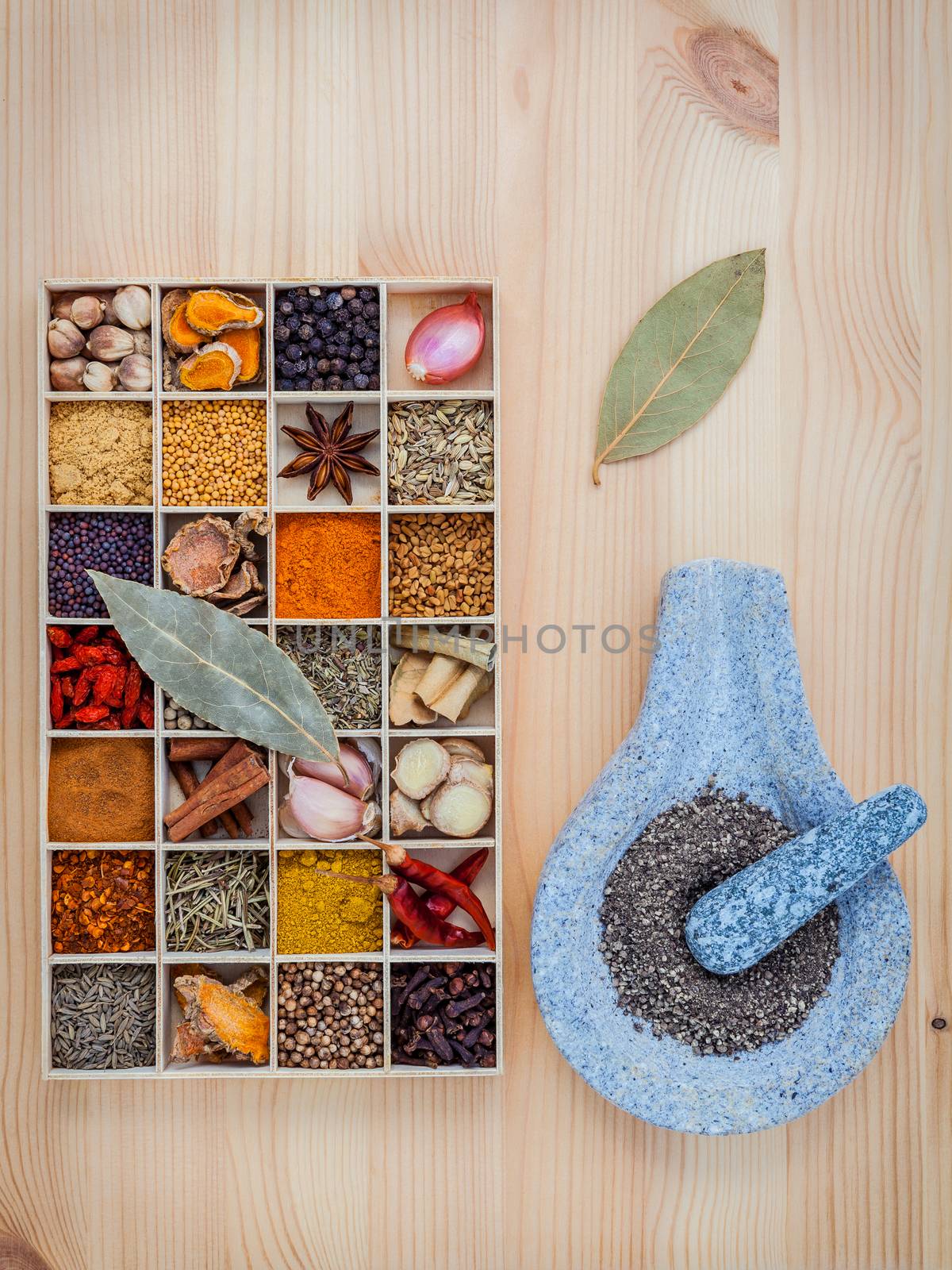 Assortment of spices food cooking ingredients in wooden box and mortar  set up on wooden table.