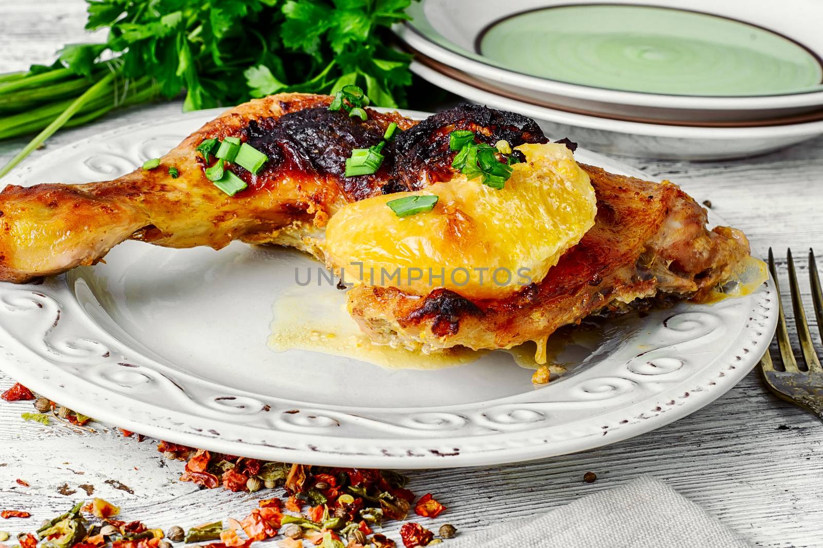 Plate of fried chicken thigh and fresh herbs.Light background