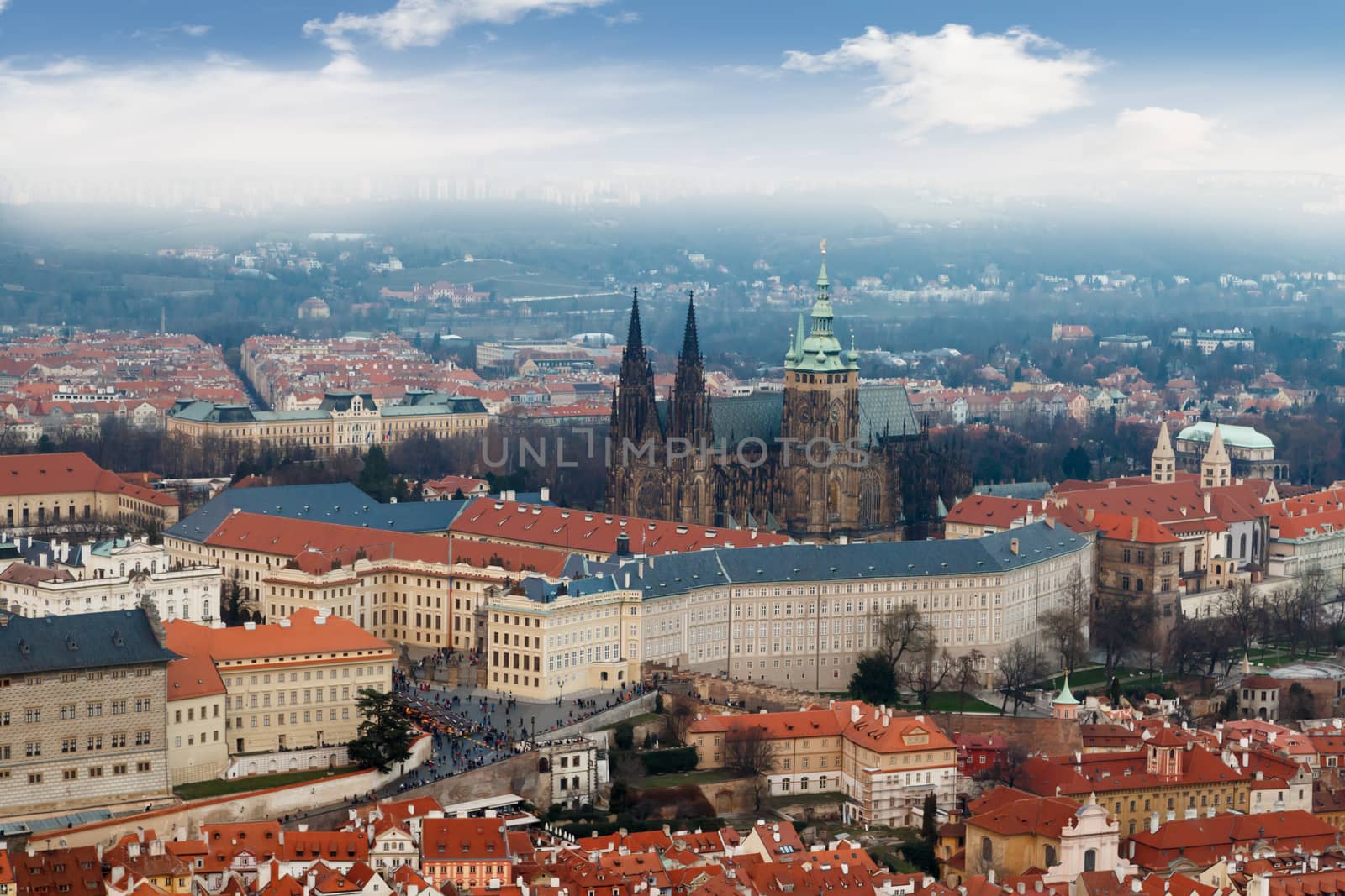 General top view of historical gothic Prague cityscape with old buildings and towers around, on cloudy sky background.