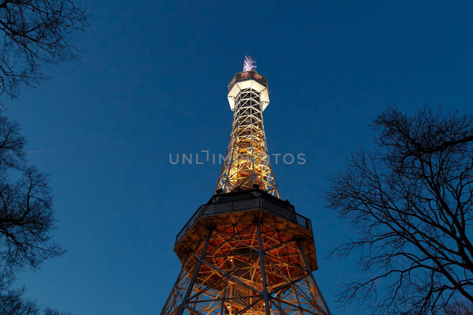 Bottom view of historical iron Petrin Tower, on bright blue sky background at sunset time.