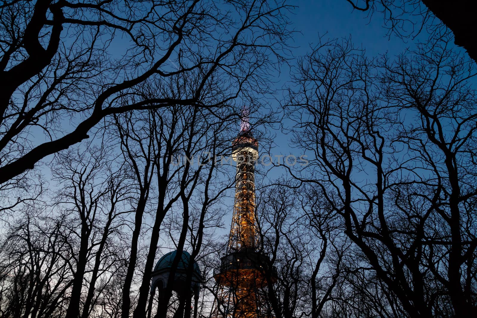 Bottom view of historical iron Petrin Tower, on bright blue sky background at sunset time.