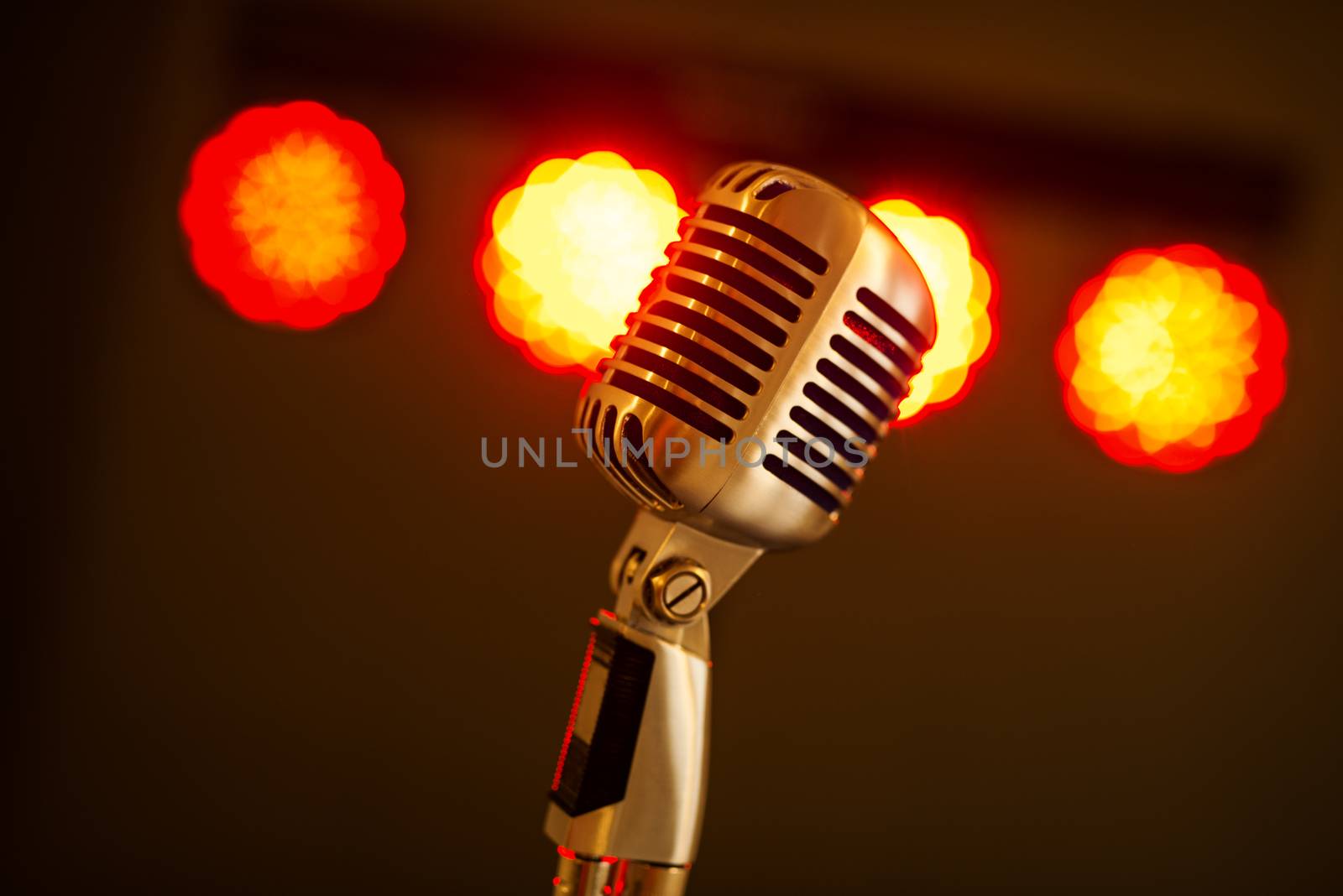Close-up of a vintage silver microphone on stage light background.