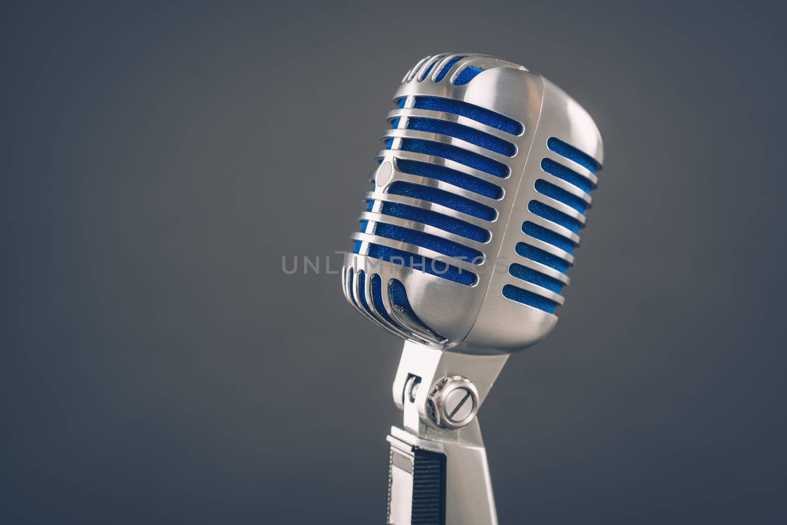 Close-up of a vintage silver microphone on blue background.