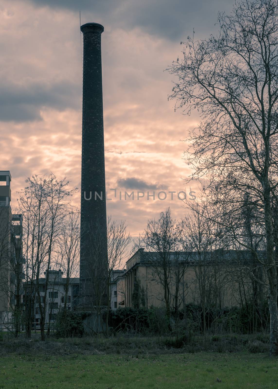 In the picture a large chimney located close to homes, split toning color used.