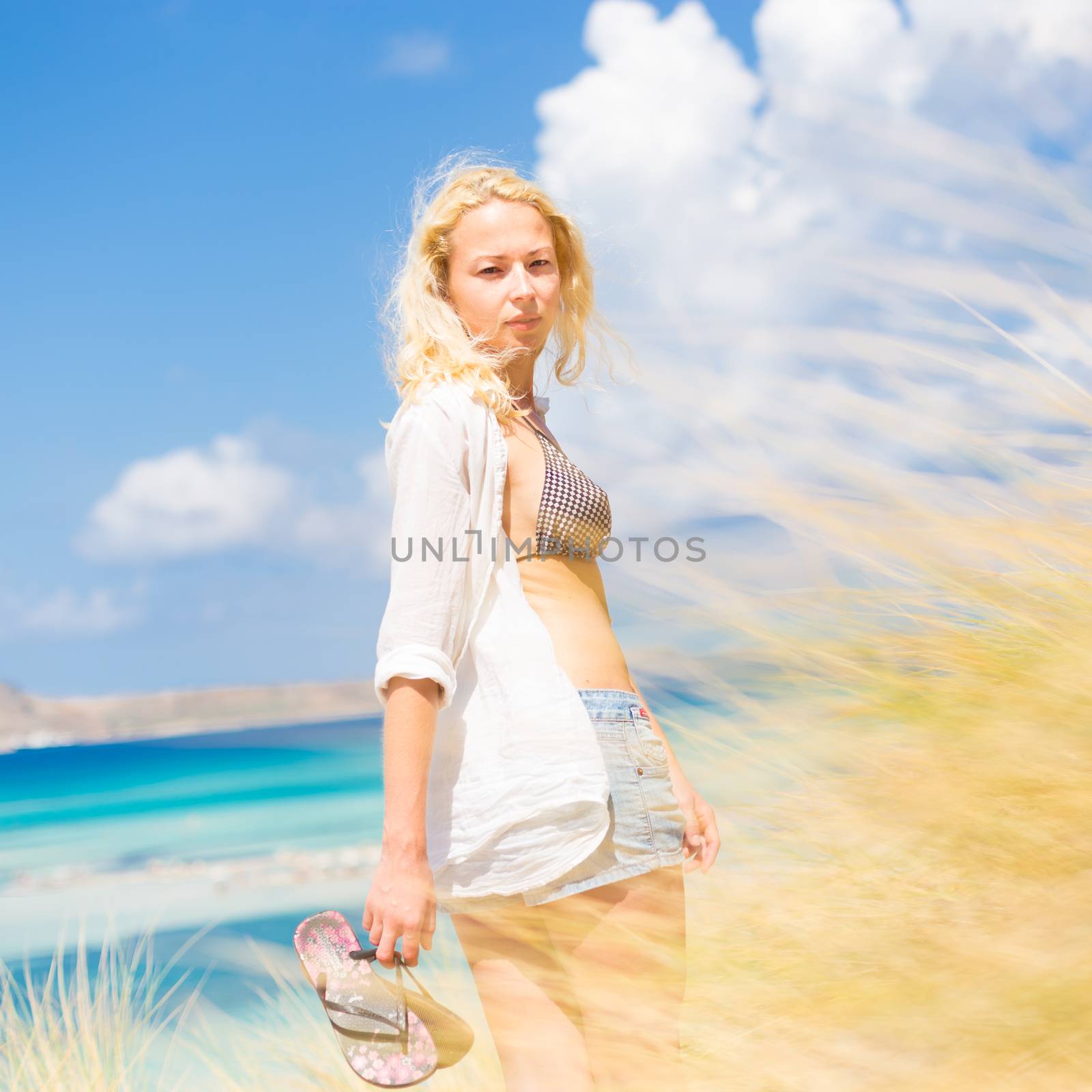 Relaxed woman enjoying freedom and life an a beautiful sandy beach.  Young lady feeling free, relaxed and happy. Concept of freedom, happiness, enjoyment and well being.  Enjoying Sun on Vacations.