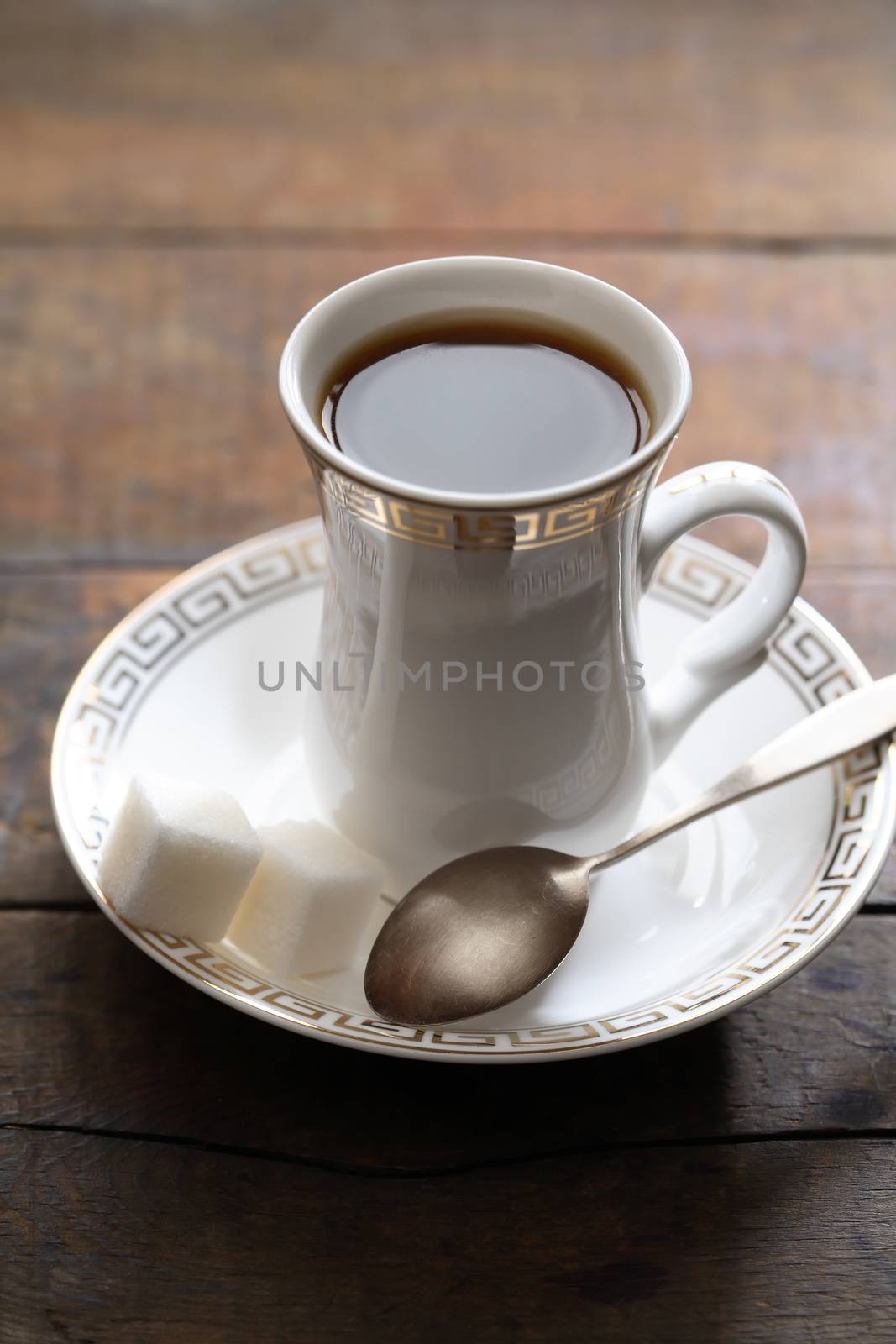 Cup of black coffee and sugar on wooden background