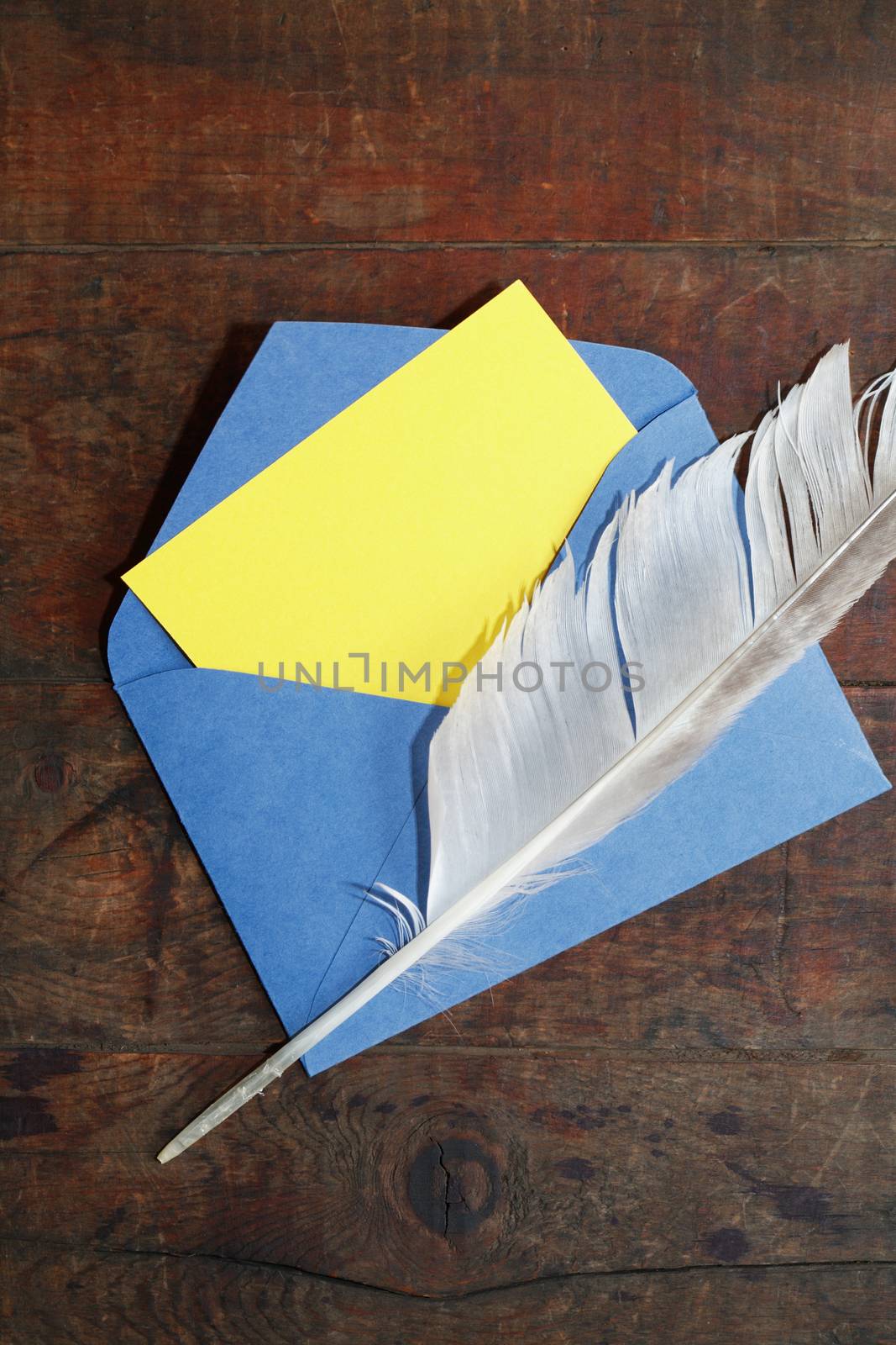 Blank yellow paper inside open envelope on wooden background