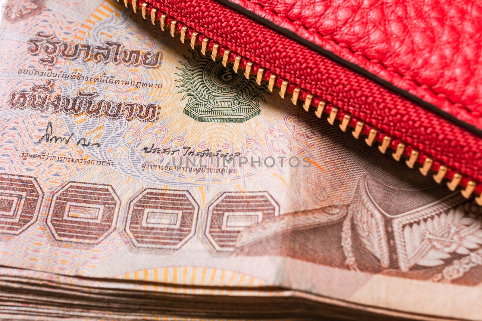 red leather wallet with thai banknote money, close up