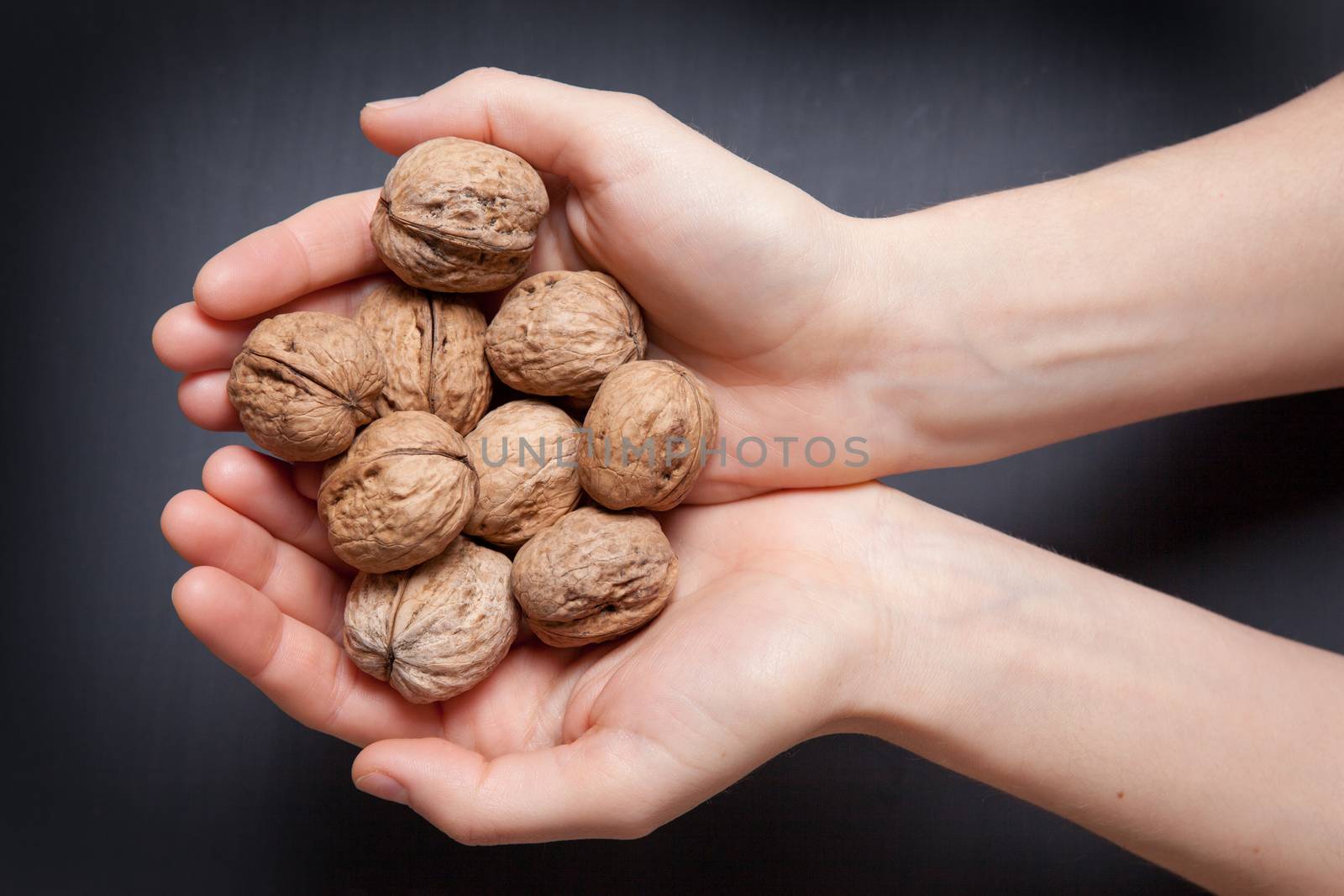 hands holding handful of walnuts over wooden table. view from the top