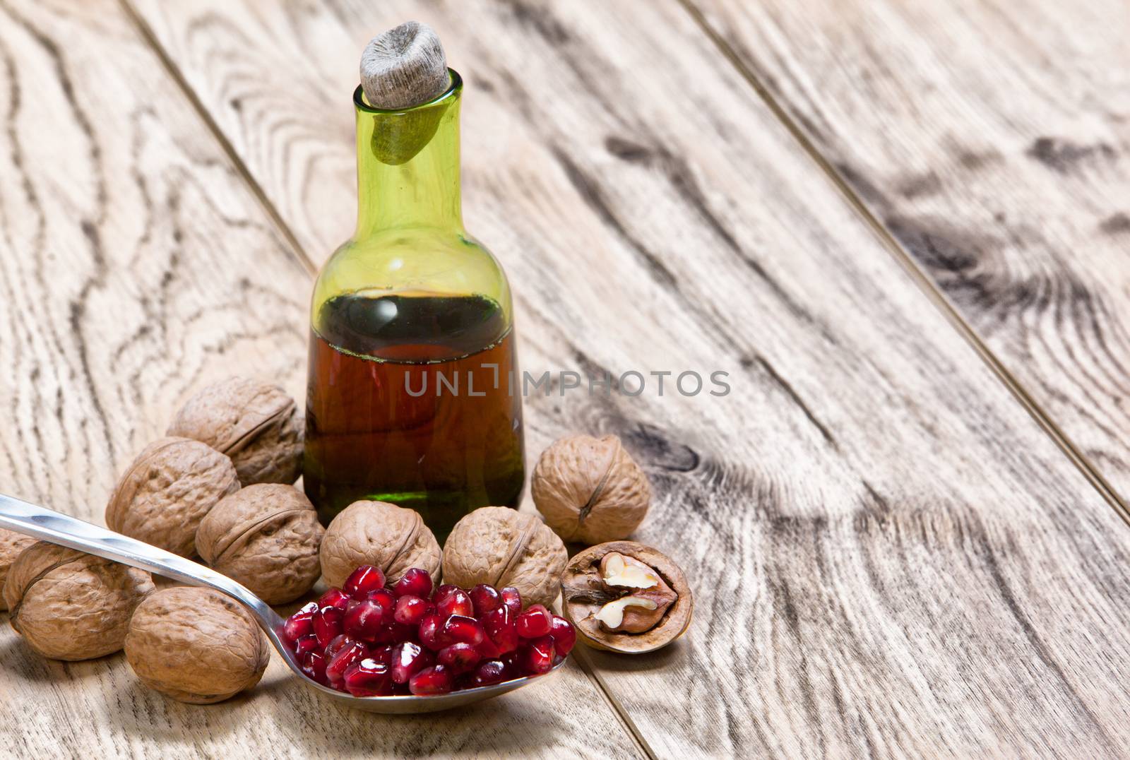 Tincture or juice of Pomegranate and ripe red seeds in an iron spoon on old wooden textured table