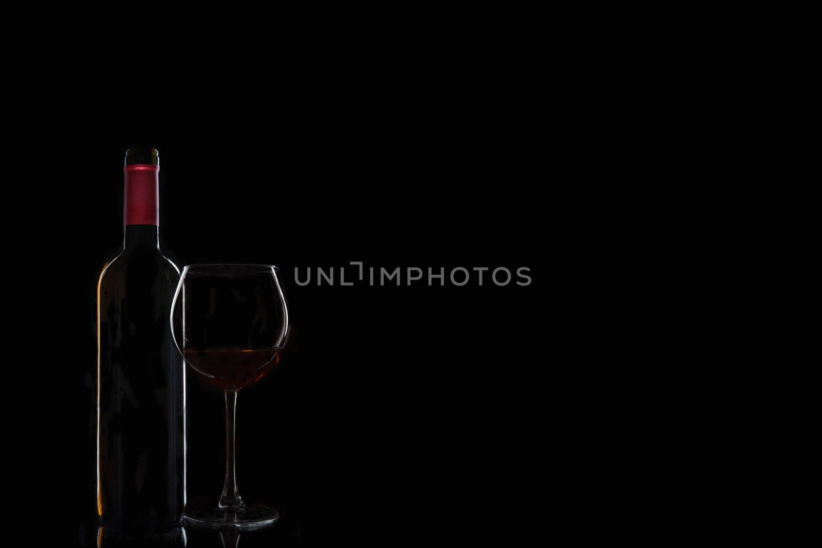 bottle of wine with a glass on a black background