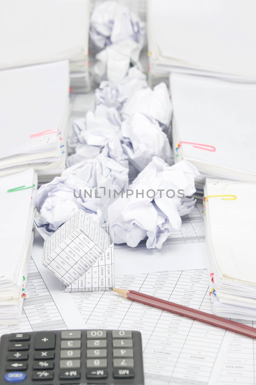 Bankruptcy of house with pencil on finance account have blur calculator and paper ball between pile of paperwork as foreground and background.