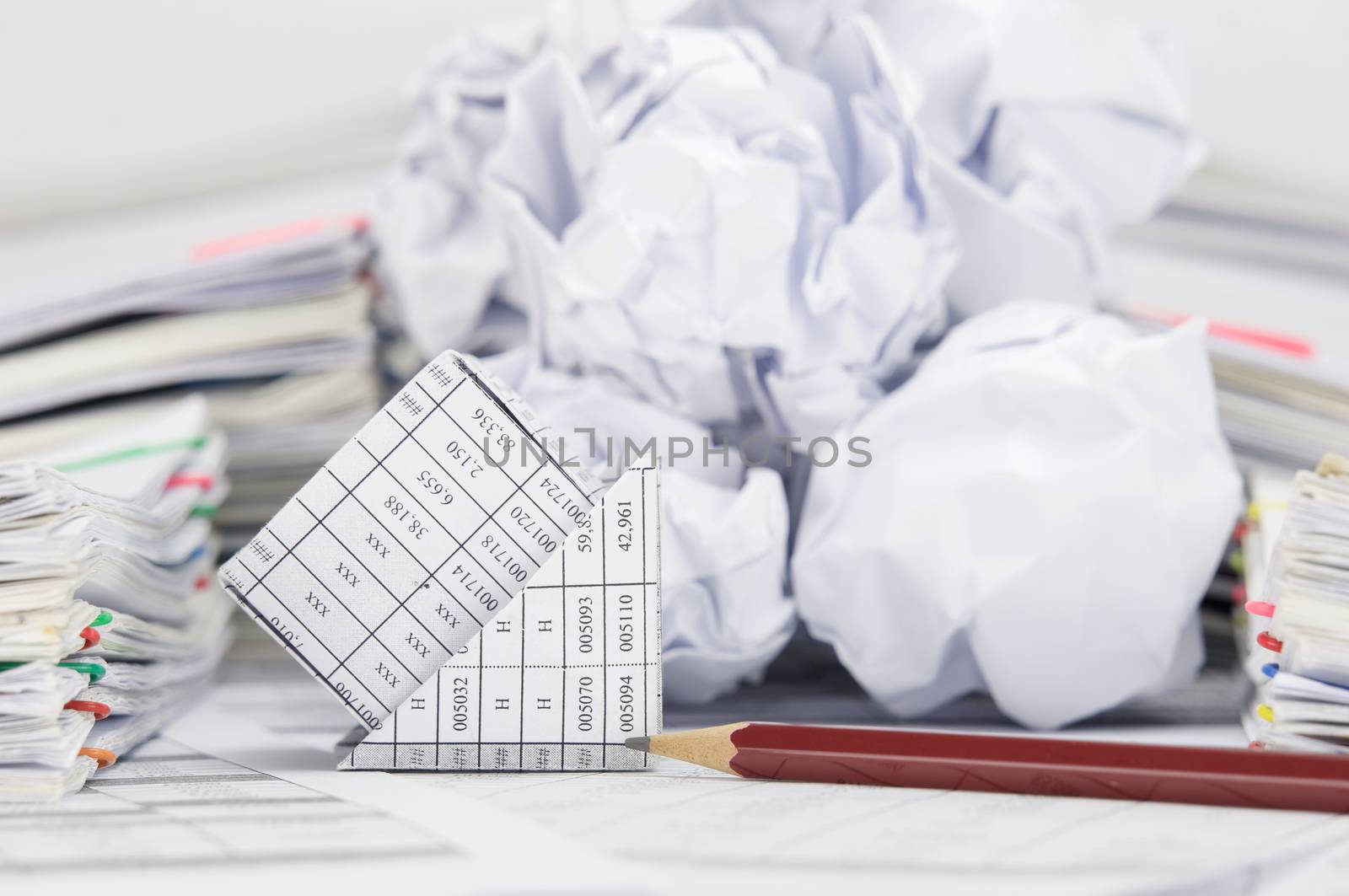 Close up bankruptcy of house with pencil on finance account have blur stack of paper ball between pile of paperwork as background.