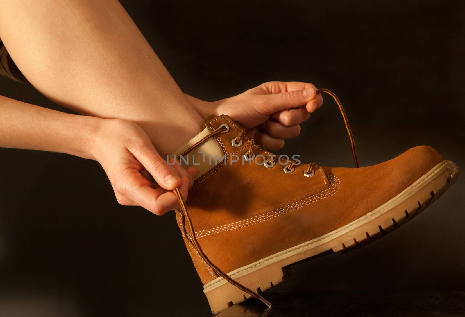 young woman hiker tying shoelaces yellow shoes. dark background