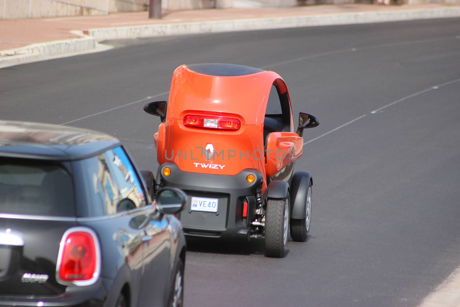 Monte-Carlo, Monaco - April 6, 2016: Red Electric Car Renault Twizy on Avenue d'Ostende in Monaco. Old Woman Driving an Electric Car Renault Twizy in the south of France