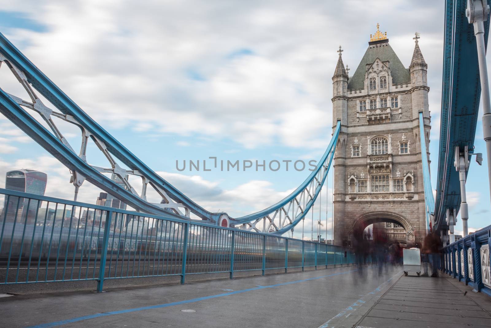 Long exposure of pedestrians crossing Tower Bridge. People have been blurred to a ghostly shape.