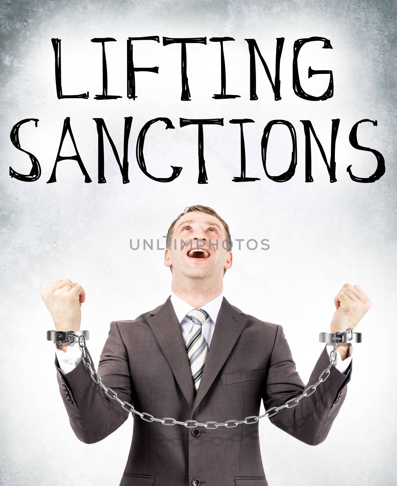 Happy businessman in cuffs looking at lifting sanctions on grey wall background