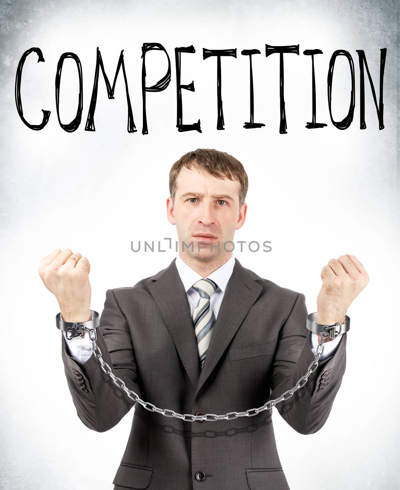Businessman in cuffs with competition word on grey wall background