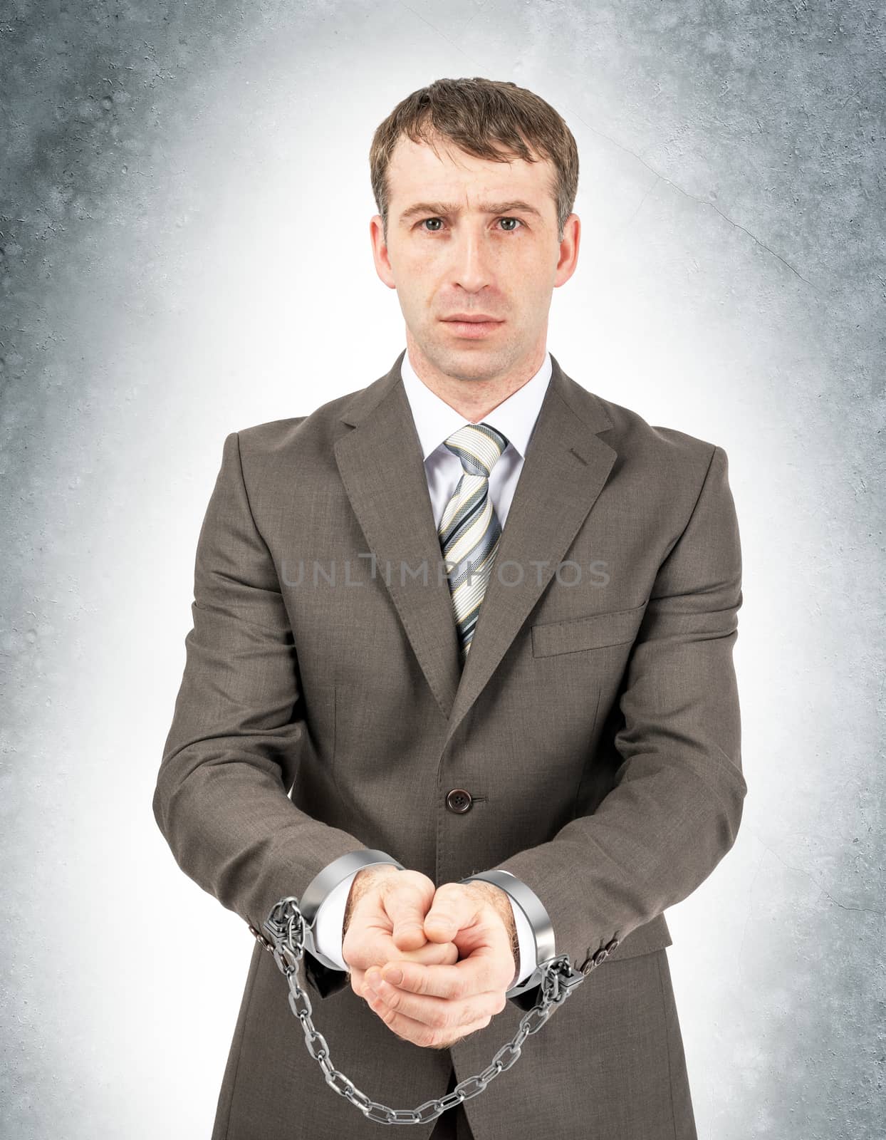 Serious businessman in cuffs on grey wall background