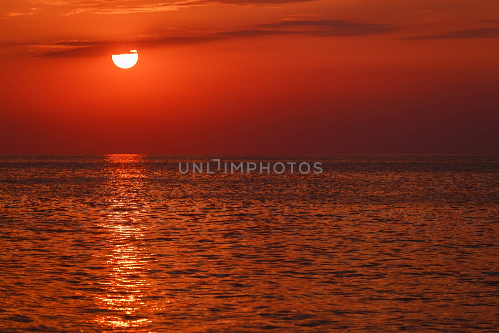 red sunset over the water. the rays of the setting sun reflected on the water surface
