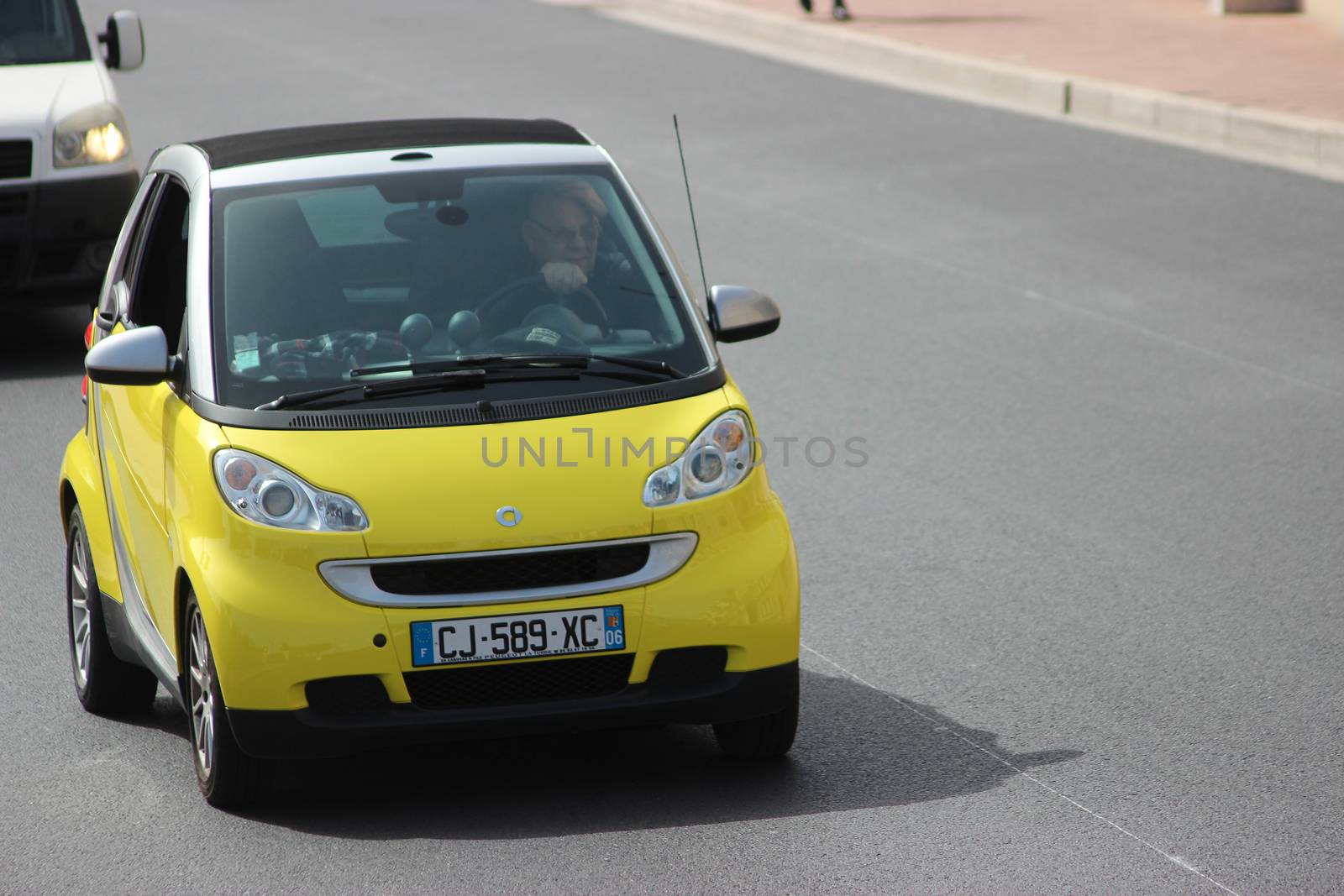 Monte-Carlo, Monaco - April 6, 2016: Yellow Compact Car Smart Fortwo on Avenue d'Ostende in Monaco. Man Driving a Yellow Car Smart Fortwo in the South of France