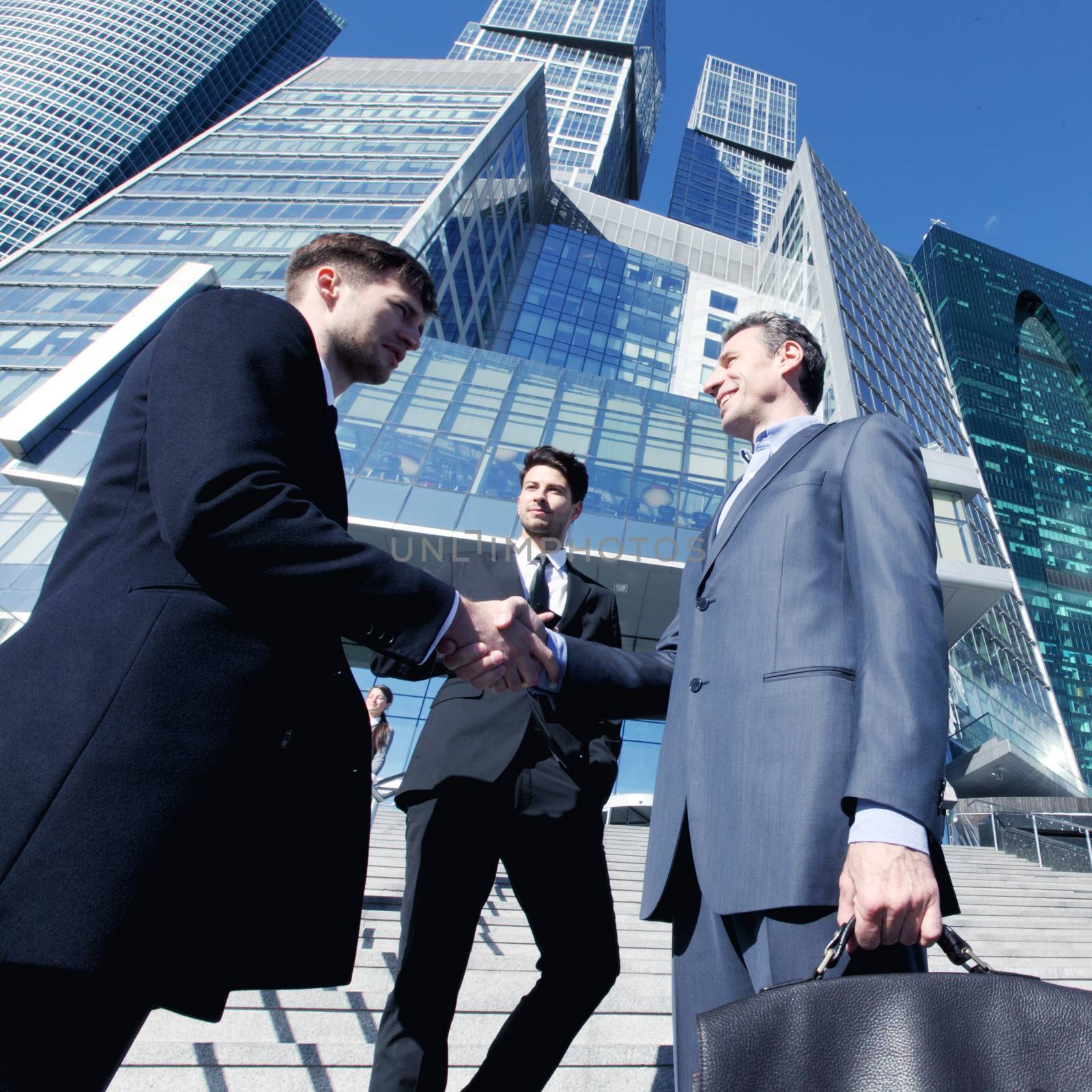 Business people shaking hands, finishing up a meeting outside office