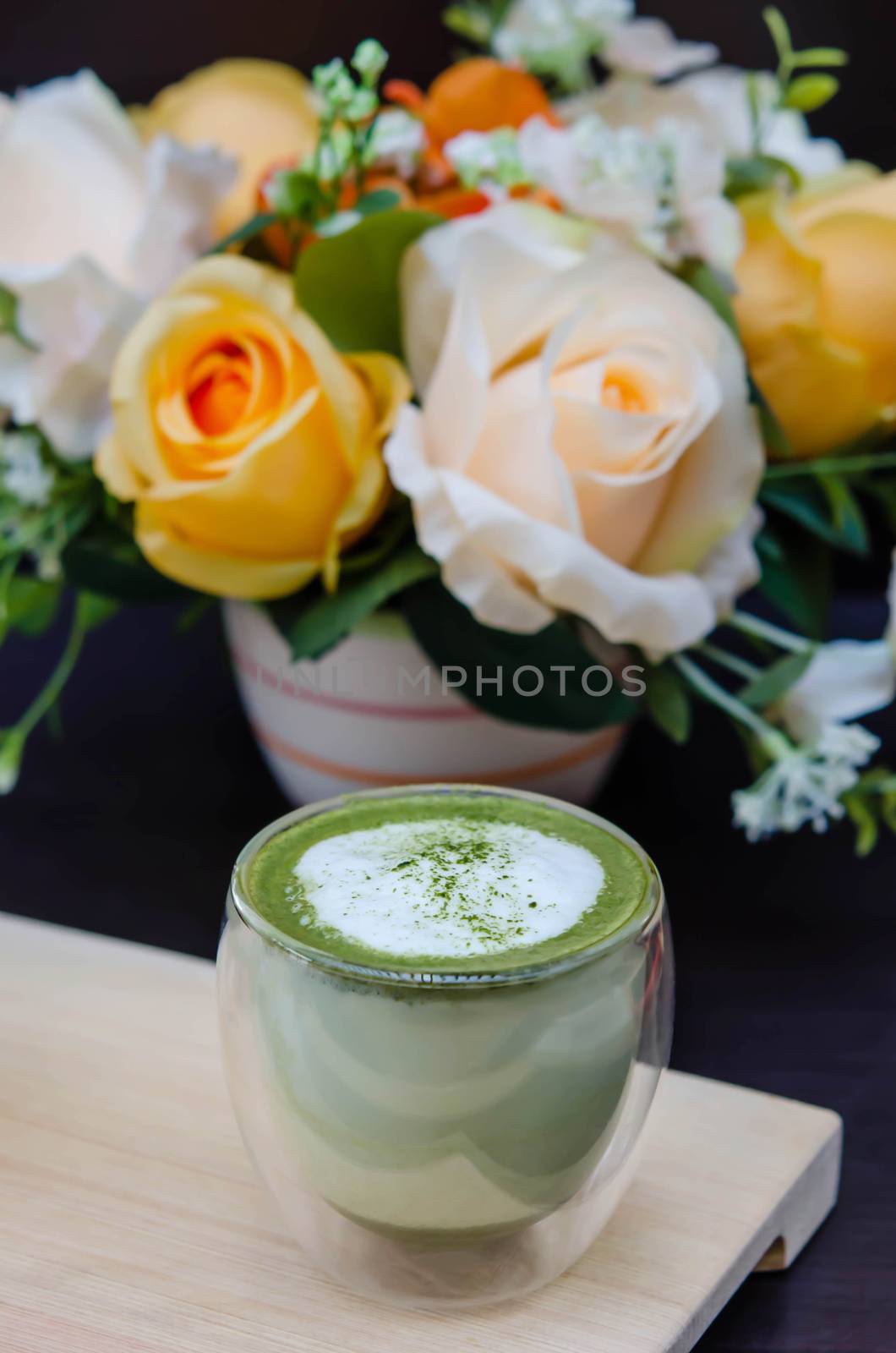 closeup cup of green tea latte on wooden plate