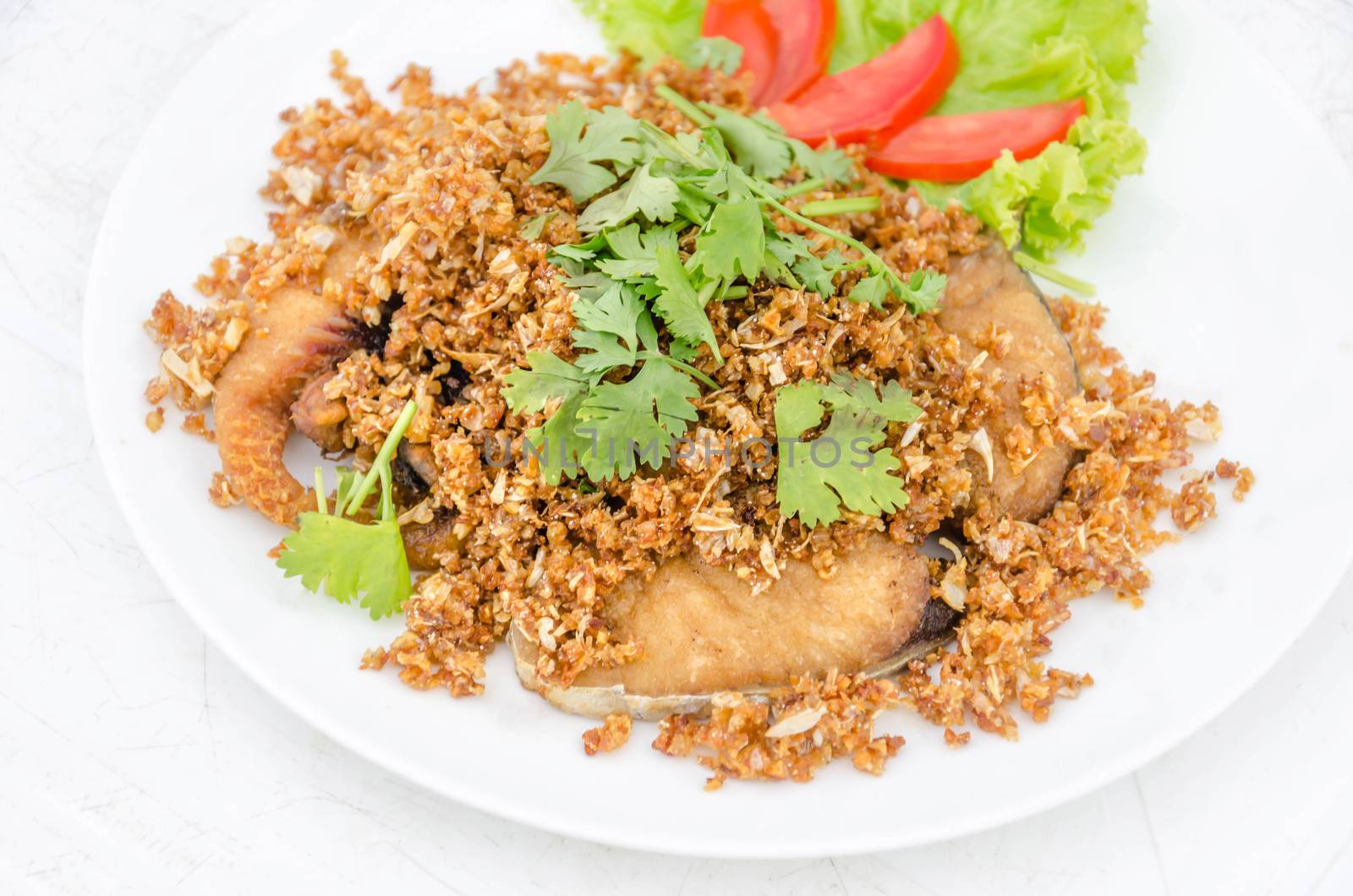 fired fish with garlic and fresh vegetable on dish