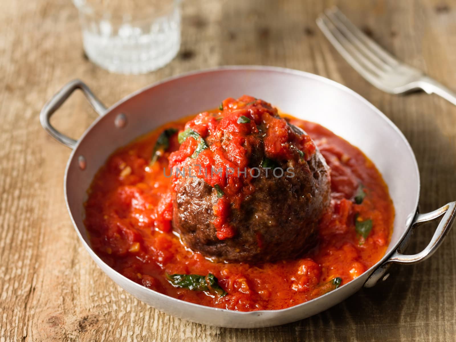 close up of rustic italian meatball in tomato sauce