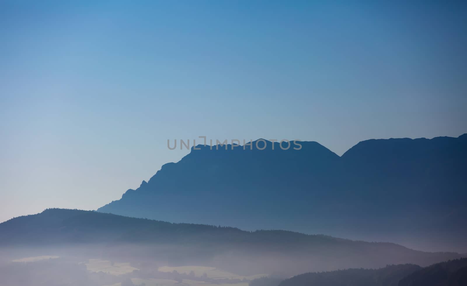 foggy hilly ground in front of a mountain chain
