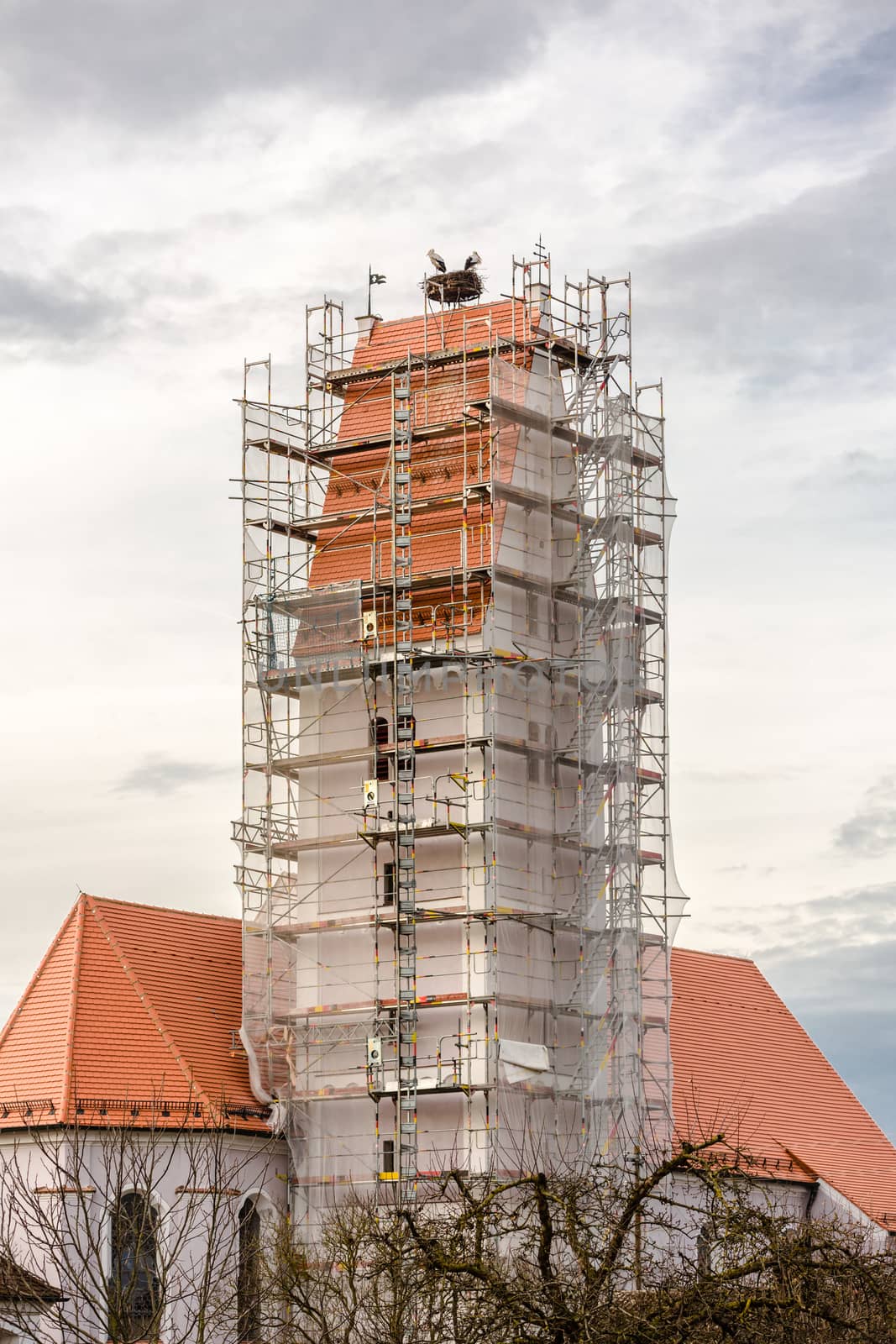 stork´s nest above a scaffolded church spire by maxlindna