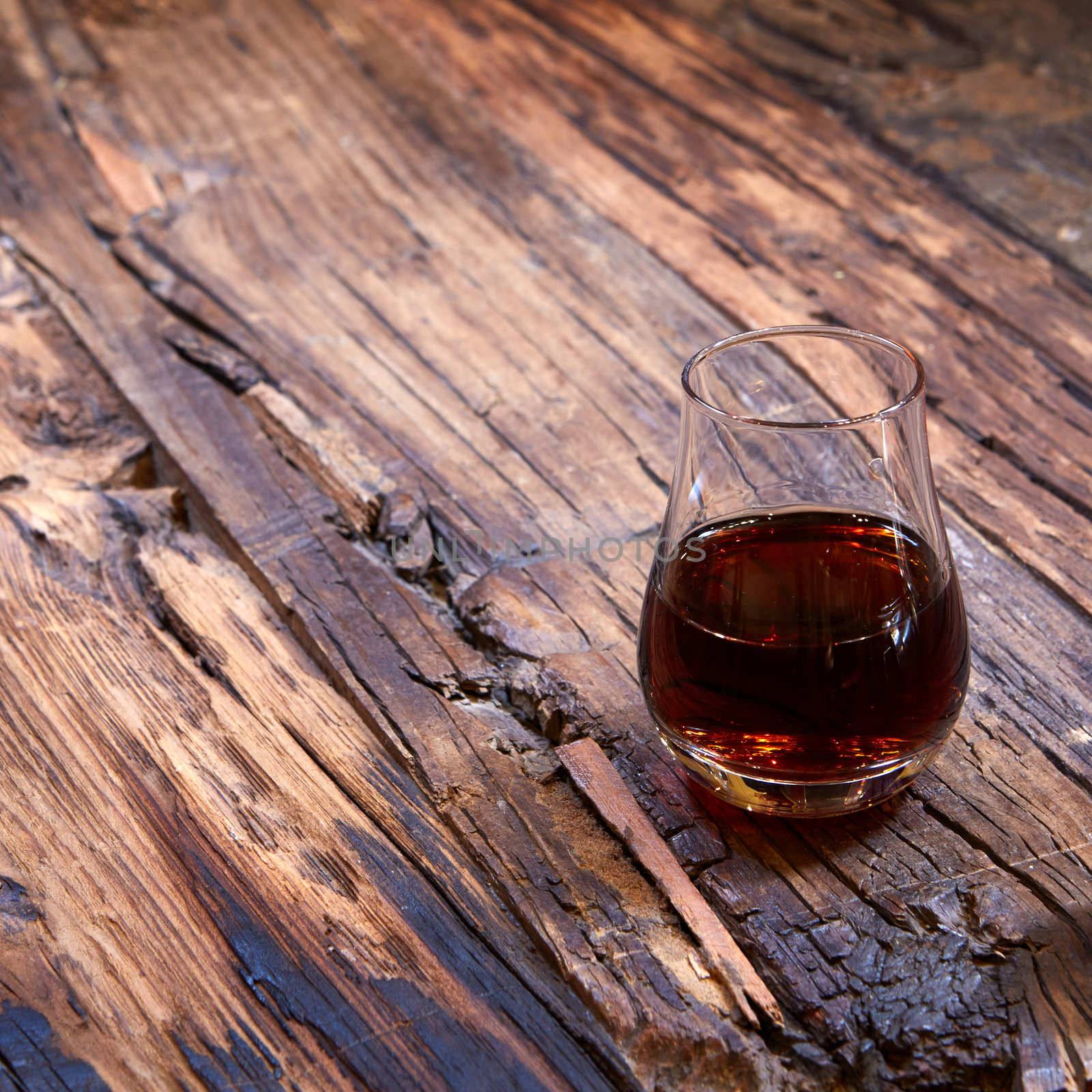 Vintage small wineglass with alcohol on old wooden background