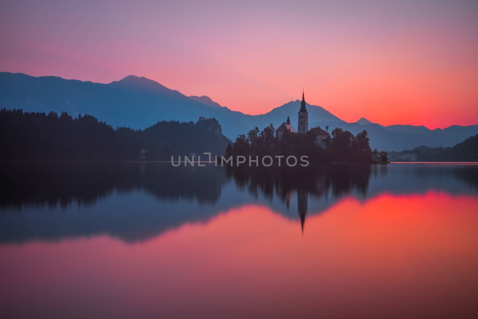 Little Island with Catholic Church in Bled Lake, Slovenia at Beautiful Red Sunrise with Castle and Mountains in Background