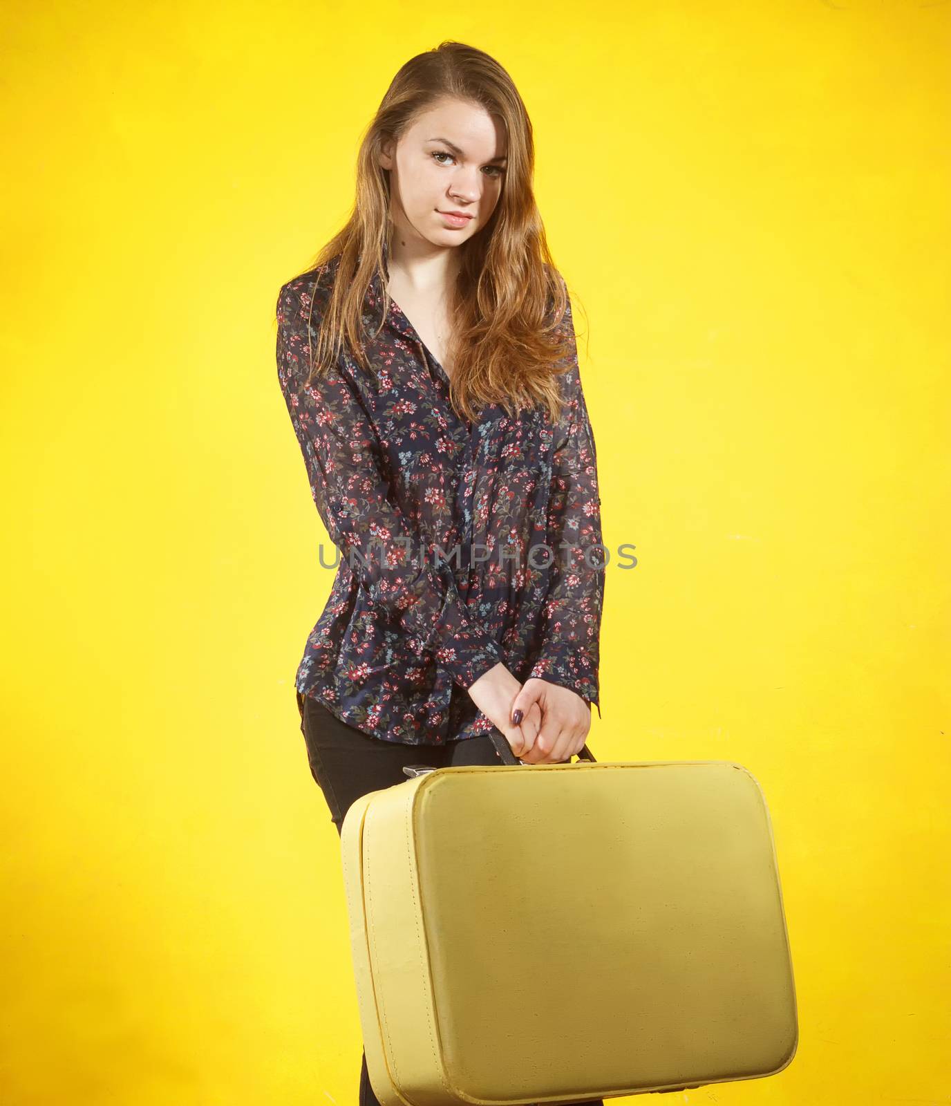 Girl with yellow suitecase on yellow background
