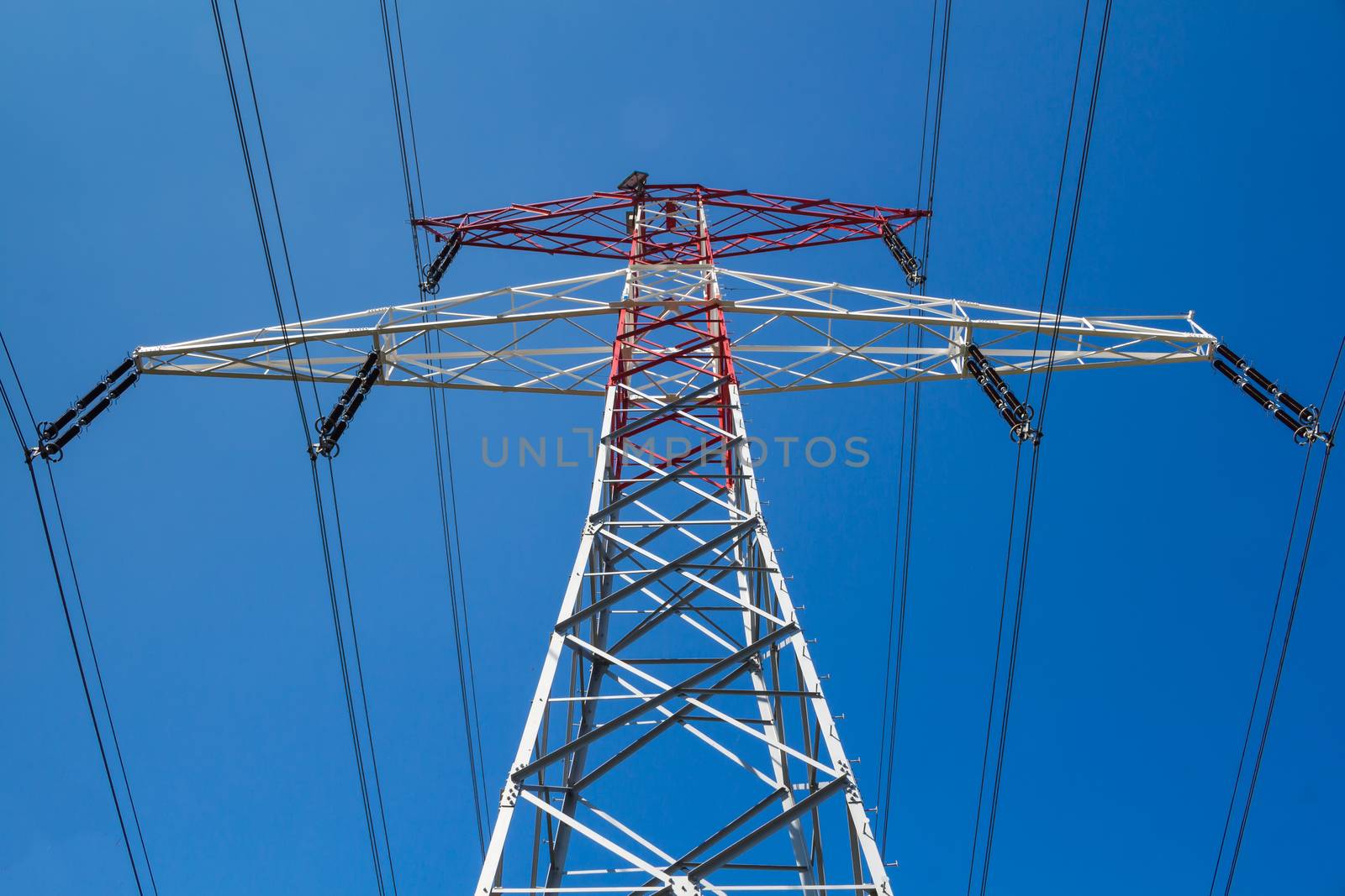 Detail of a new electricity tower, with blue sky in the background.