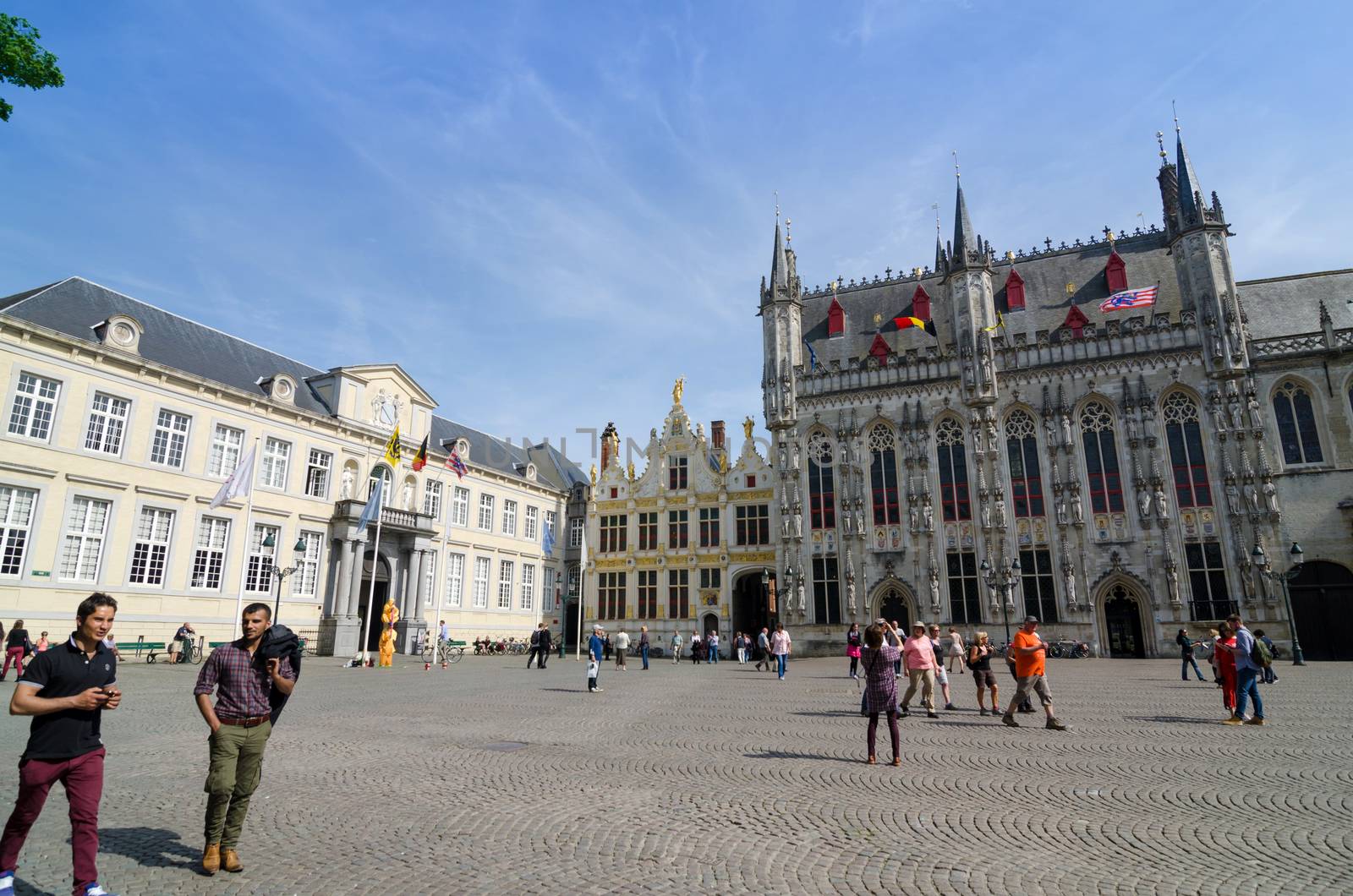 Bruges, Belgium - May 11, 2015: Tourist on Burg square with City Hall in Bruges, Belgium on May 11, 2015. The historic city centre is a prominent World Heritage Site of UNESCO.