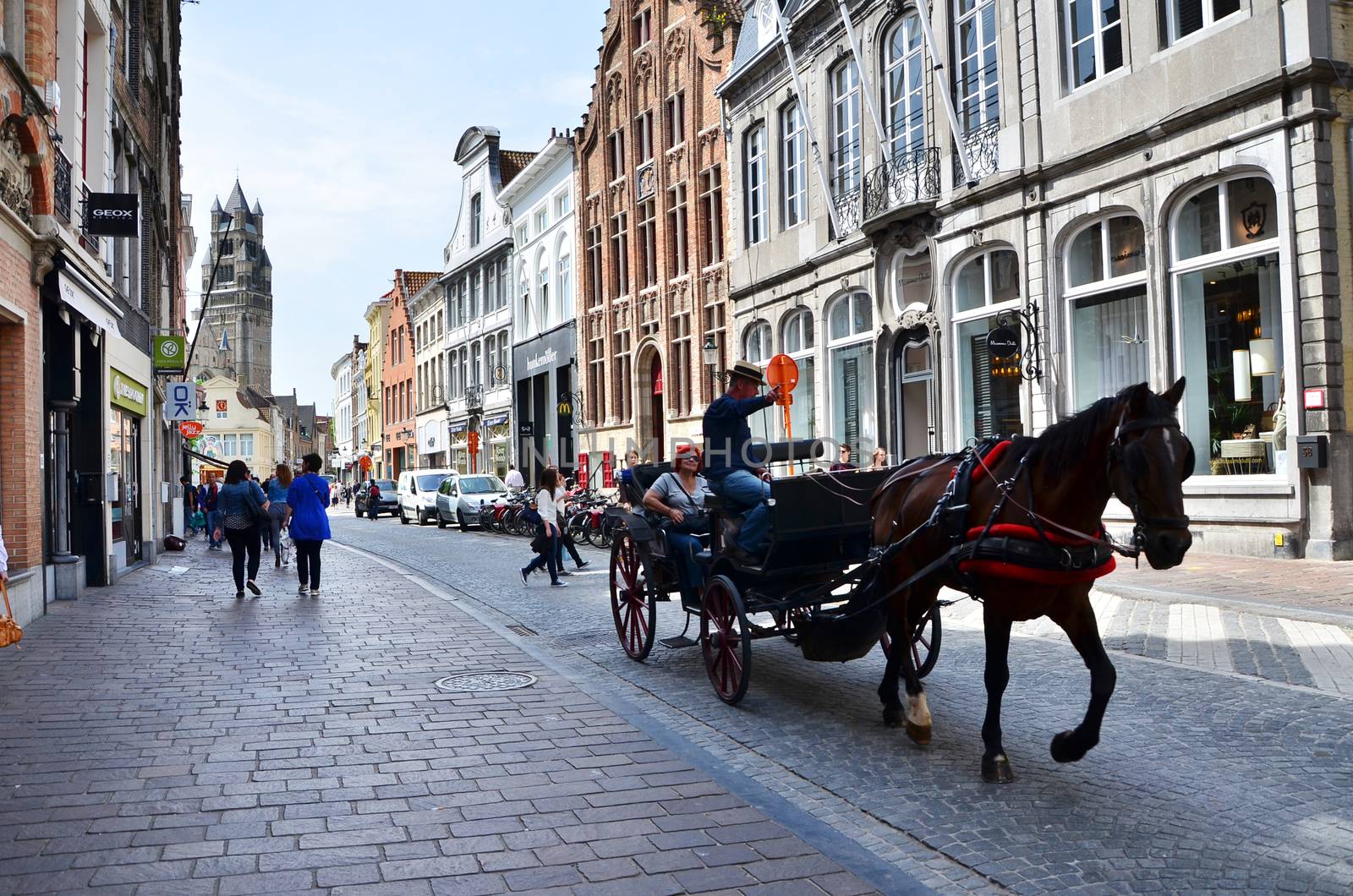 Bruges, Belgium - May 11, 2015: Tourists visit Bruges in traditional horse carriage around the city. by siraanamwong