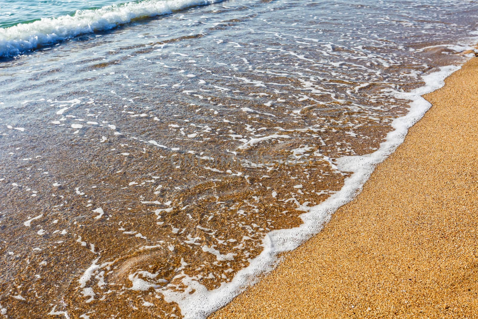 Sun light reflected on soft wave of the sea on the sandy beach