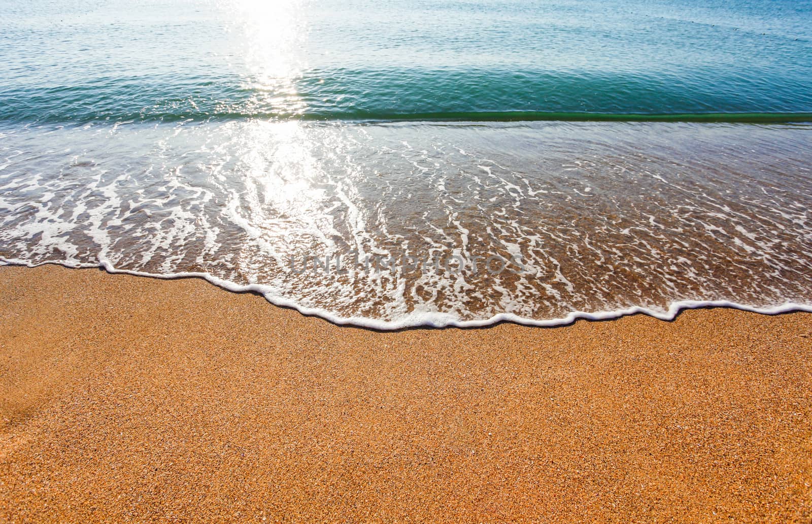 Sun light reflected on soft wave of the sea on the sandy beach