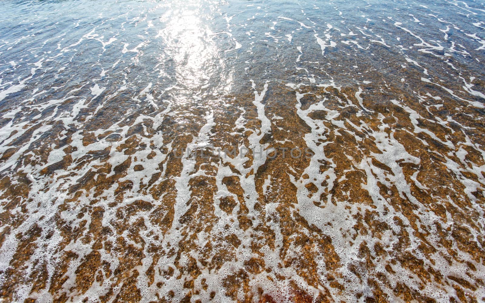 Sun light reflected on soft wave of the sea on the sandy beach