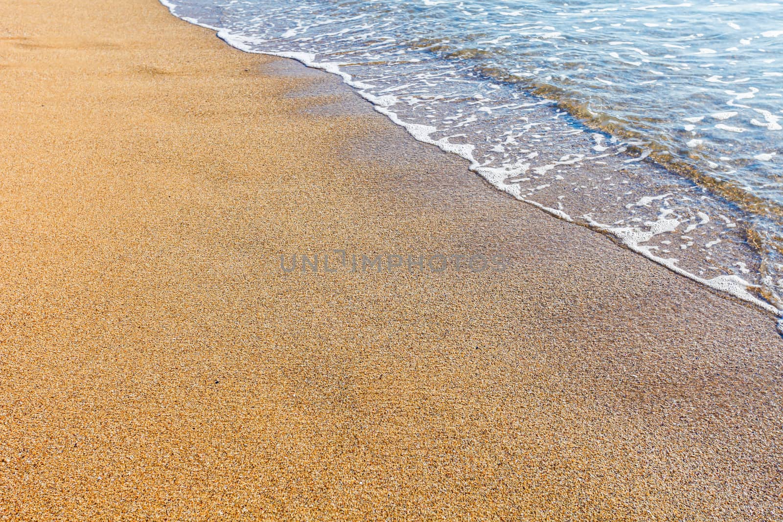 Sun light reflected on soft wave of the sea on the sandy beach