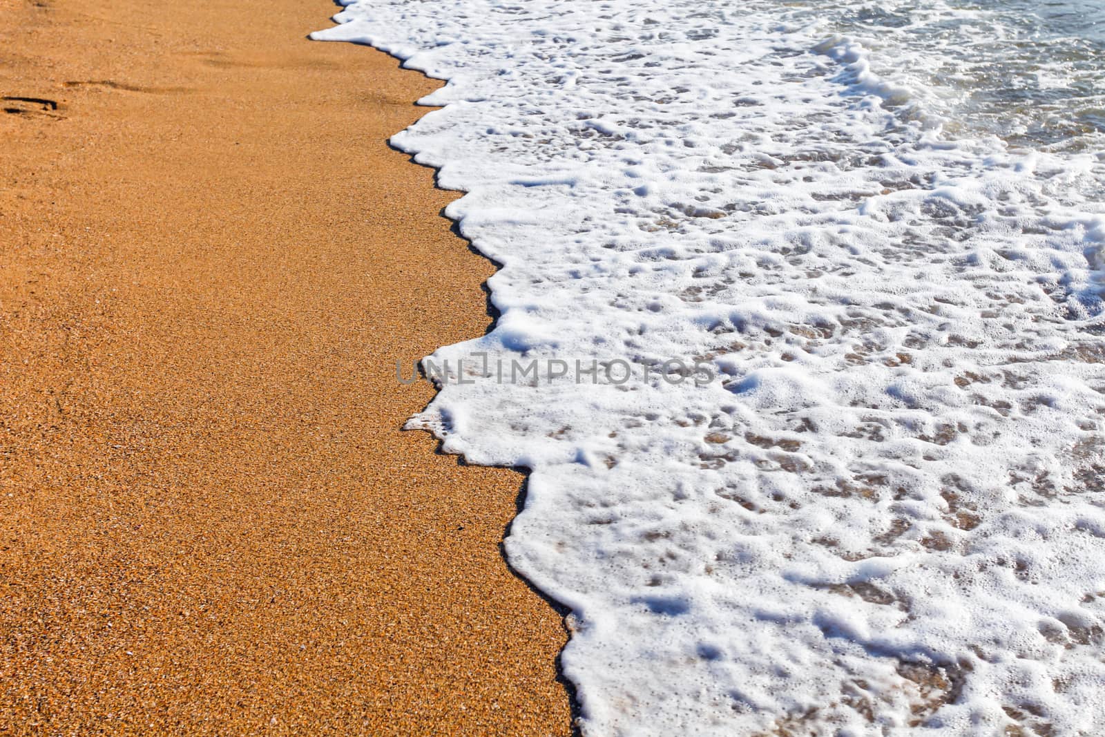 Sun light reflected on soft wave of the sea on the sandy beach