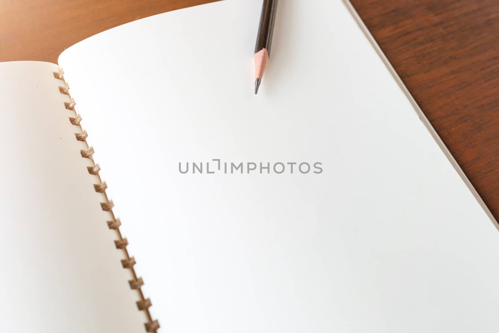 Blank note book with pencil on wooden table background concept a by nopparats